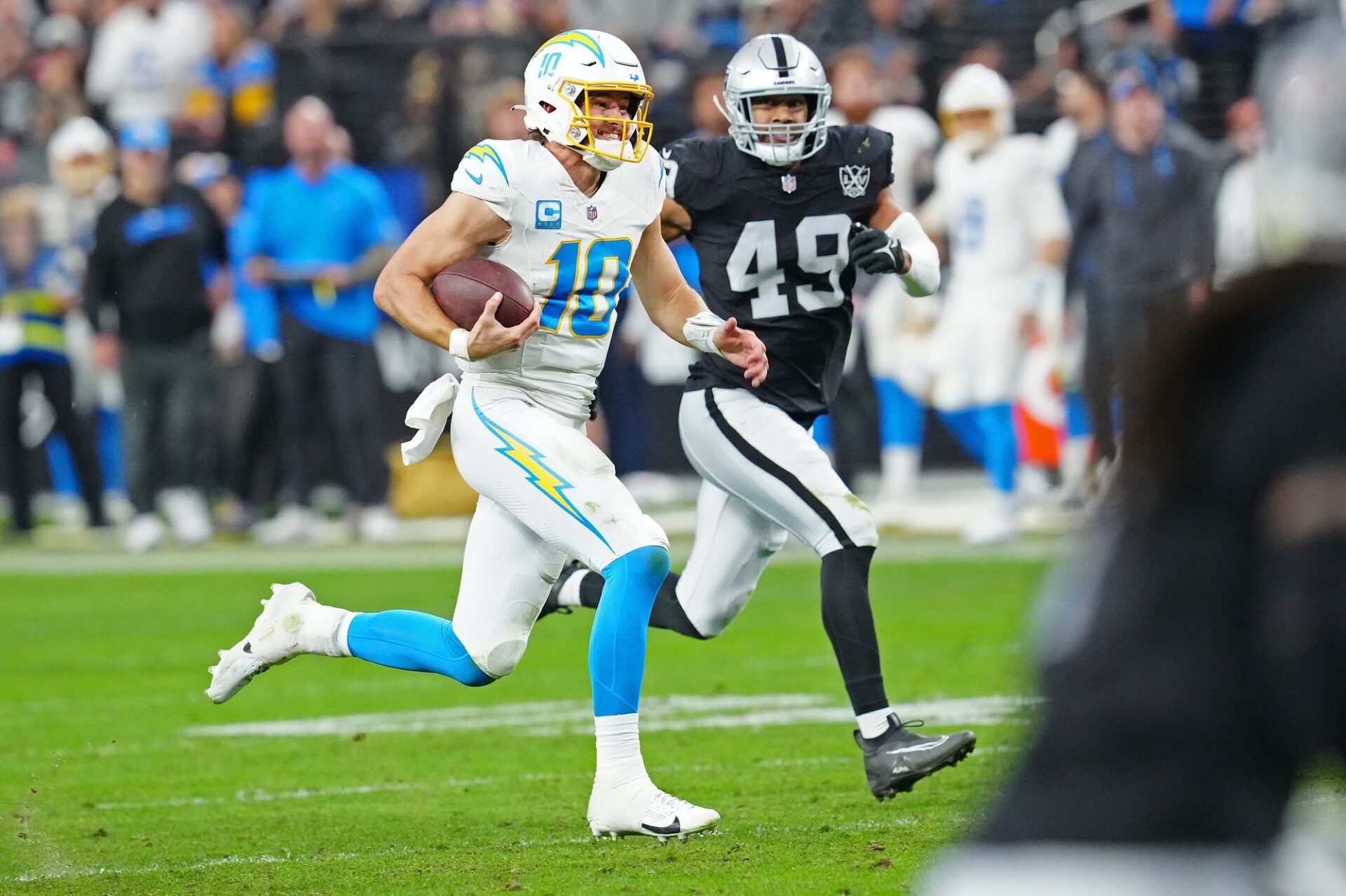 Los Angeles Chargers quarterback Justin Herbert (10) gains yardage ahead of Las Vegas Raiders defensive end Charles Snowden (49) during the fourth quarter at Allegiant Stadium.