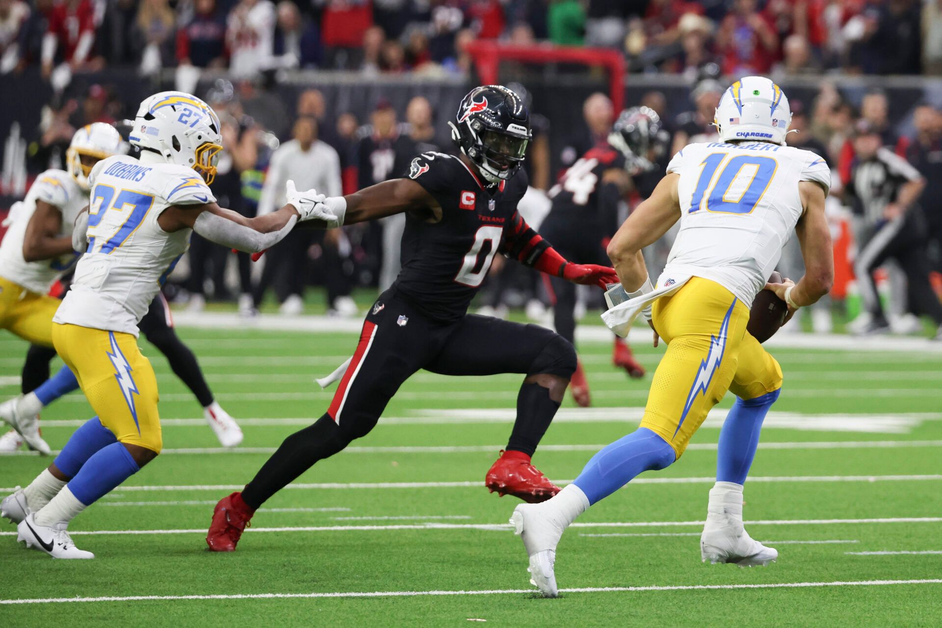 Jan 11, 2025; Houston, Texas, USA; Los Angeles Chargers quarterback Justin Herbert (10) scrambles from Houston Texans linebacker Azeez Al-Shaair (0) in the second quarter in an AFC wild card game at NRG Stadium. Mandatory Credit: Thomas Shea-Imagn Images