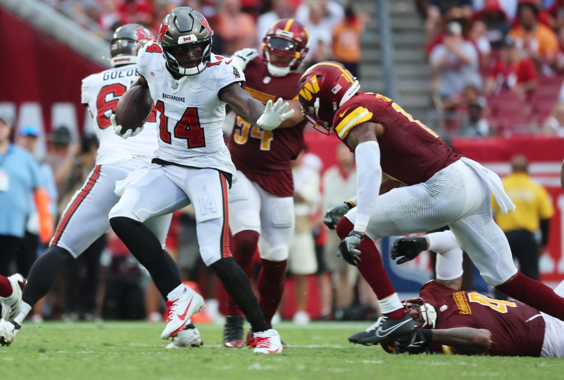 Sep 8, 2024; Tampa, Florida, USA;T ampa Bay Buccaneers wide receiver Chris Godwin (14) stiff arms Washington Commanders safety Jeremy Chinn (11) during the second half at Raymond James Stadium. Mandatory Credit: Kim Klement Neitzel-Imagn Images