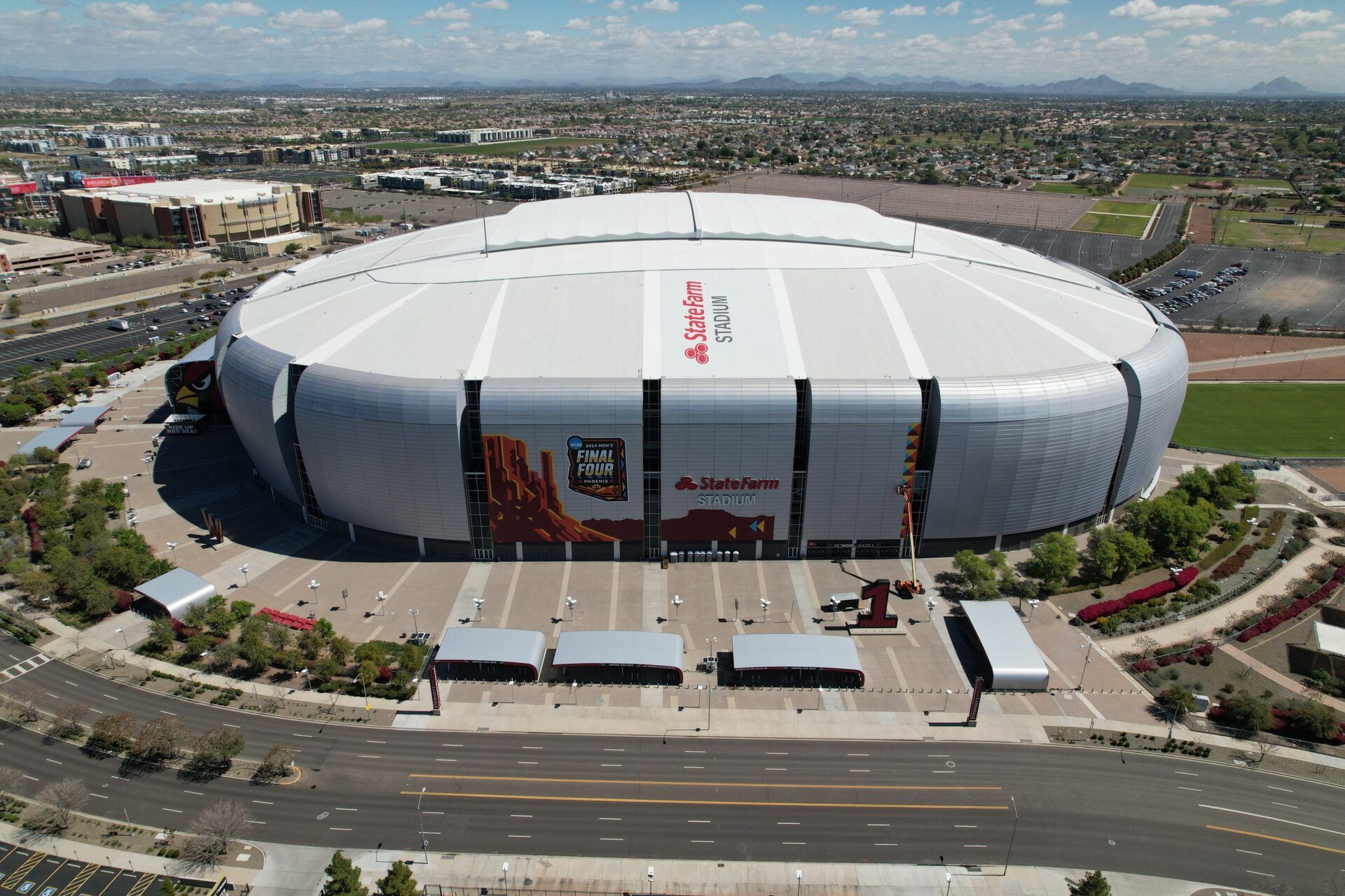 Workers install logos on the exterior of State Farm Stadium in preparations for the Final Four April 6-8, 2024.