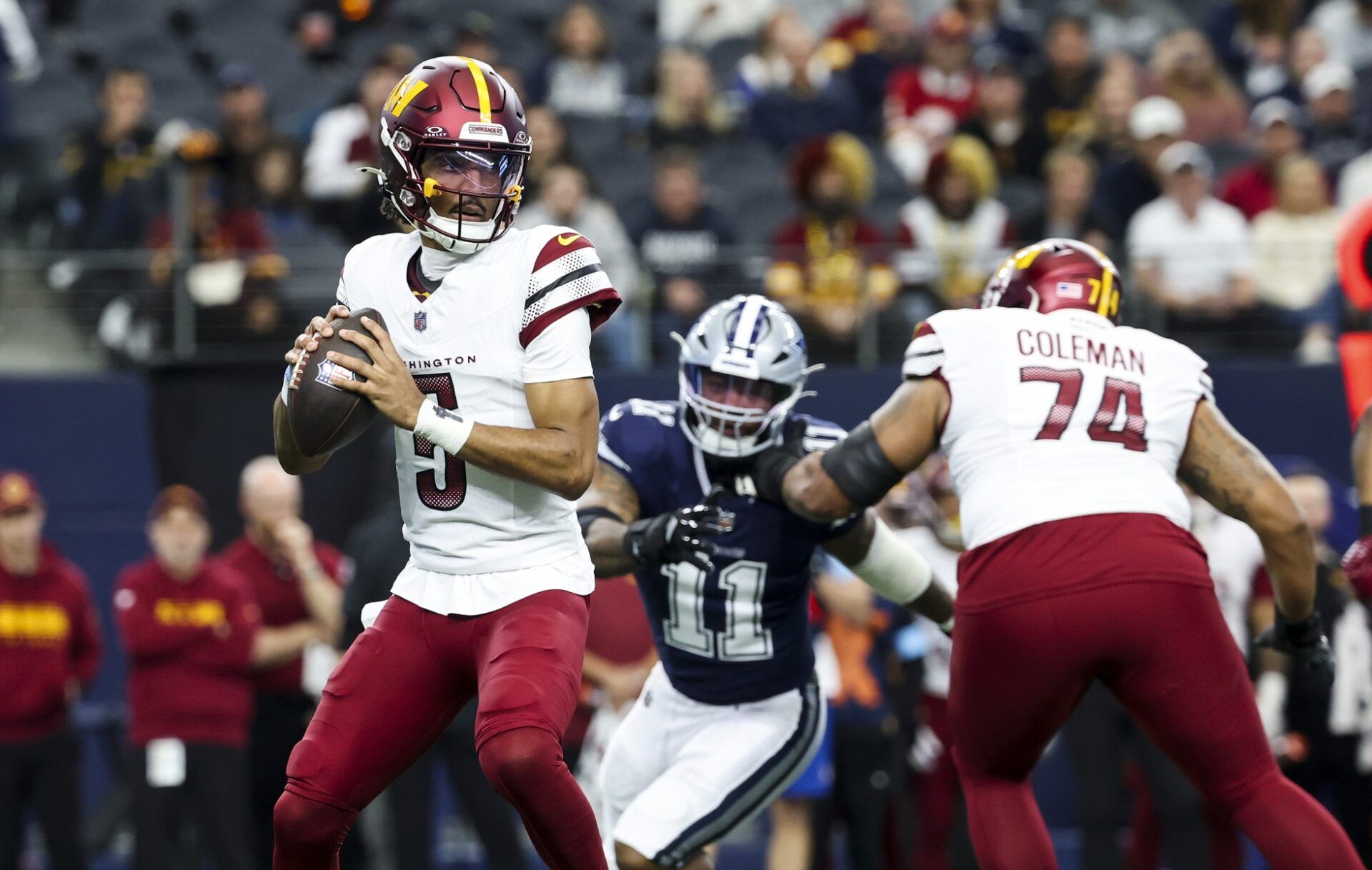 Washington Commanders quarterback Jayden Daniels (5) throws as Dallas Cowboys linebacker Micah Parsons (11) chases during the first quarter at AT&T Stadium.