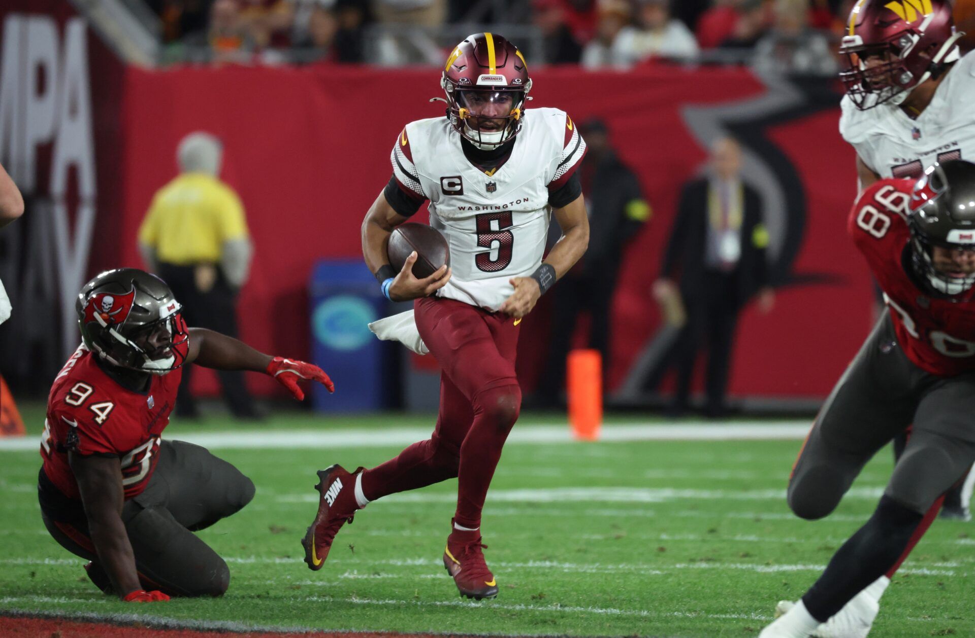 Washington Commanders quarterback Jayden Daniels (5) scrambles against Tampa Bay Buccaneers defensive tackle Calijah Kancey (94) during the second quarter of a NFC wild card playoff at Raymond James Stadium.