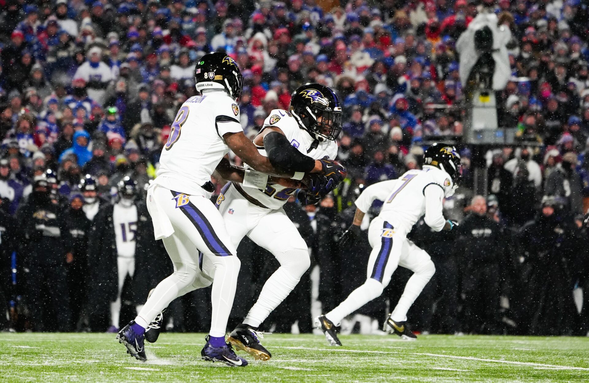 Baltimore Ravens quarterback Lamar Jackson (8) hands the ball off to Baltimore Ravens running back Derrick Henry (22) during the first quarter against the Buffalo Bills in a 2025 AFC divisional round game at Highmark Stadium.