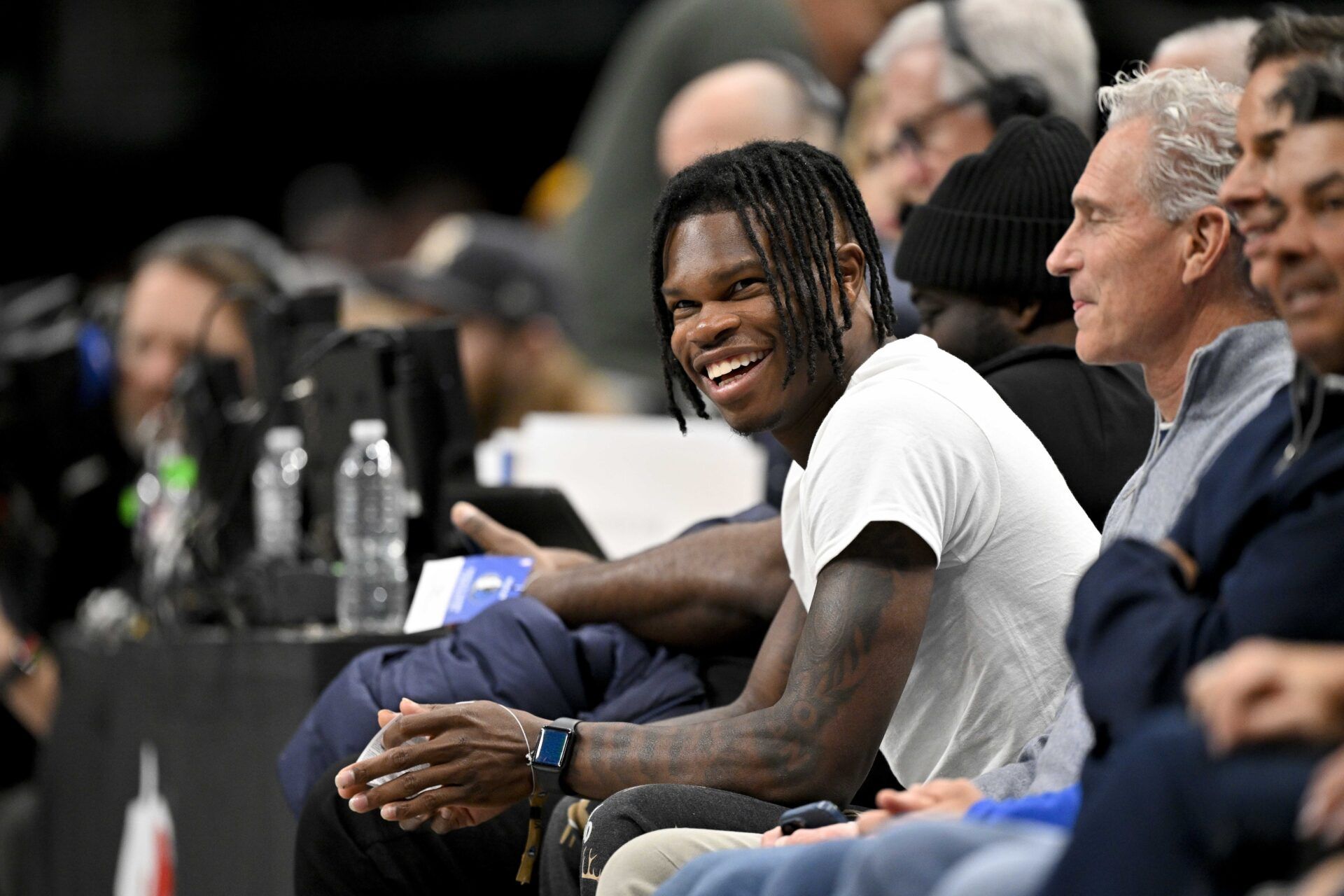 Heisman Trophy winner Travis Hunter Jr. laughs during the second half of the game between the Dallas Mavericks and the Minnesota Timberwolves at the American Airlines Center.