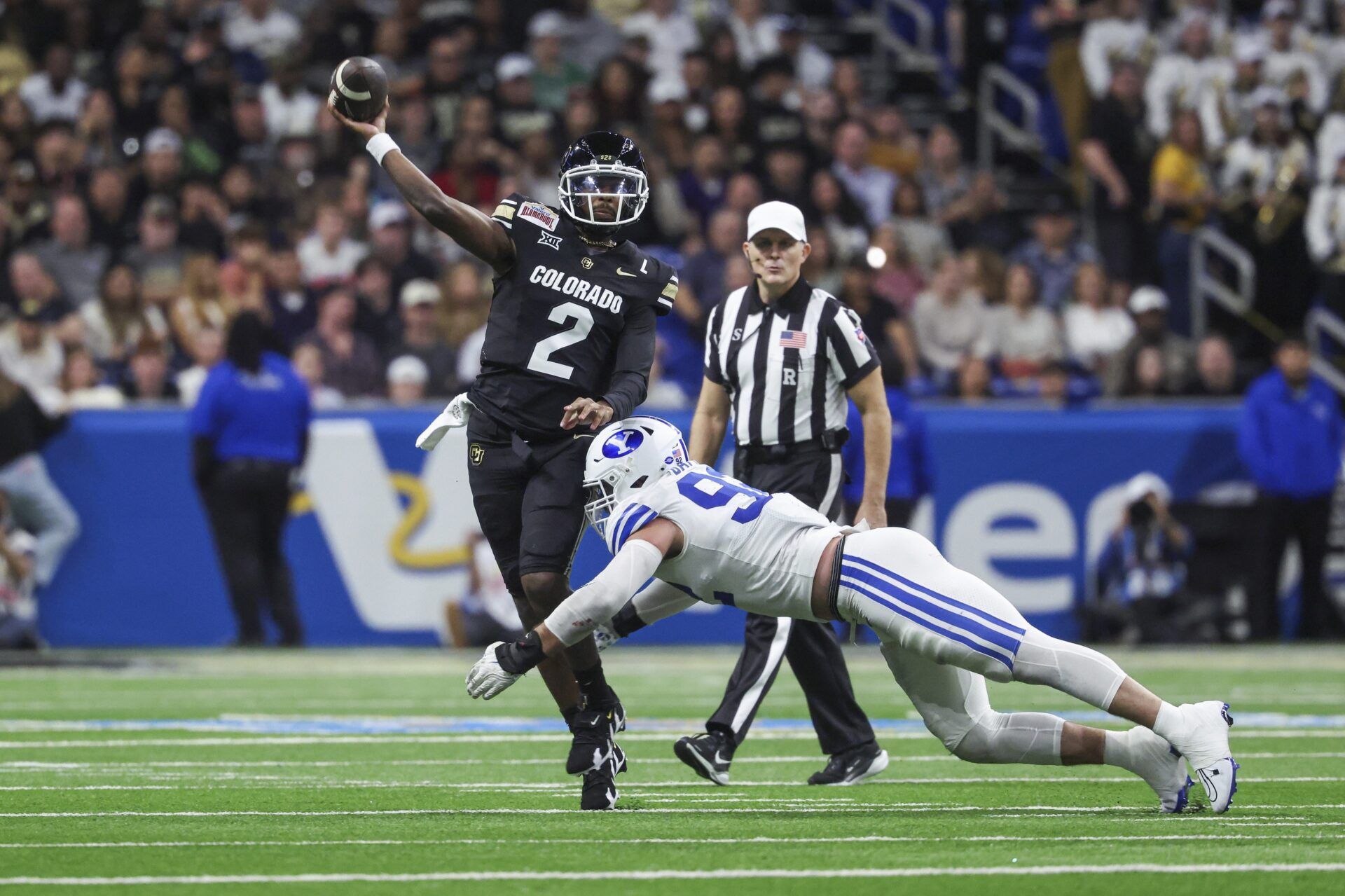 Colorado Buffaloes quarterback Shedeur Sanders (2) attempts a pass as Brigham Young Cougars defensive end Tyler Batty (92) attempts to make a tackle during the third quarter at Alamodome.