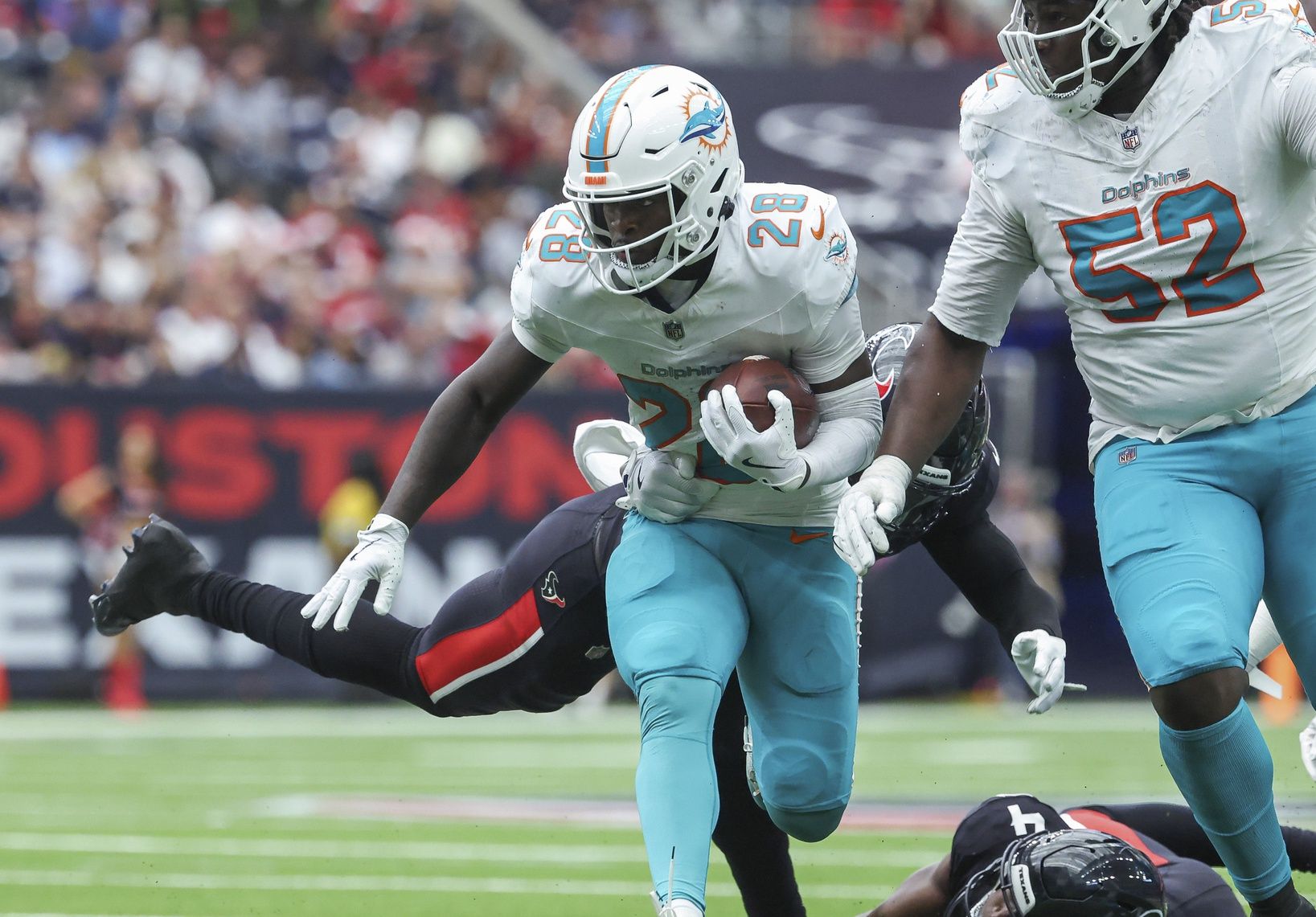 Miami Dolphins running back De'Von Achane (28) runs with the ball as Houston Texans linebacker Christian Harris (48) attempts to make a tackle during the second quarter at NRG Stadium.