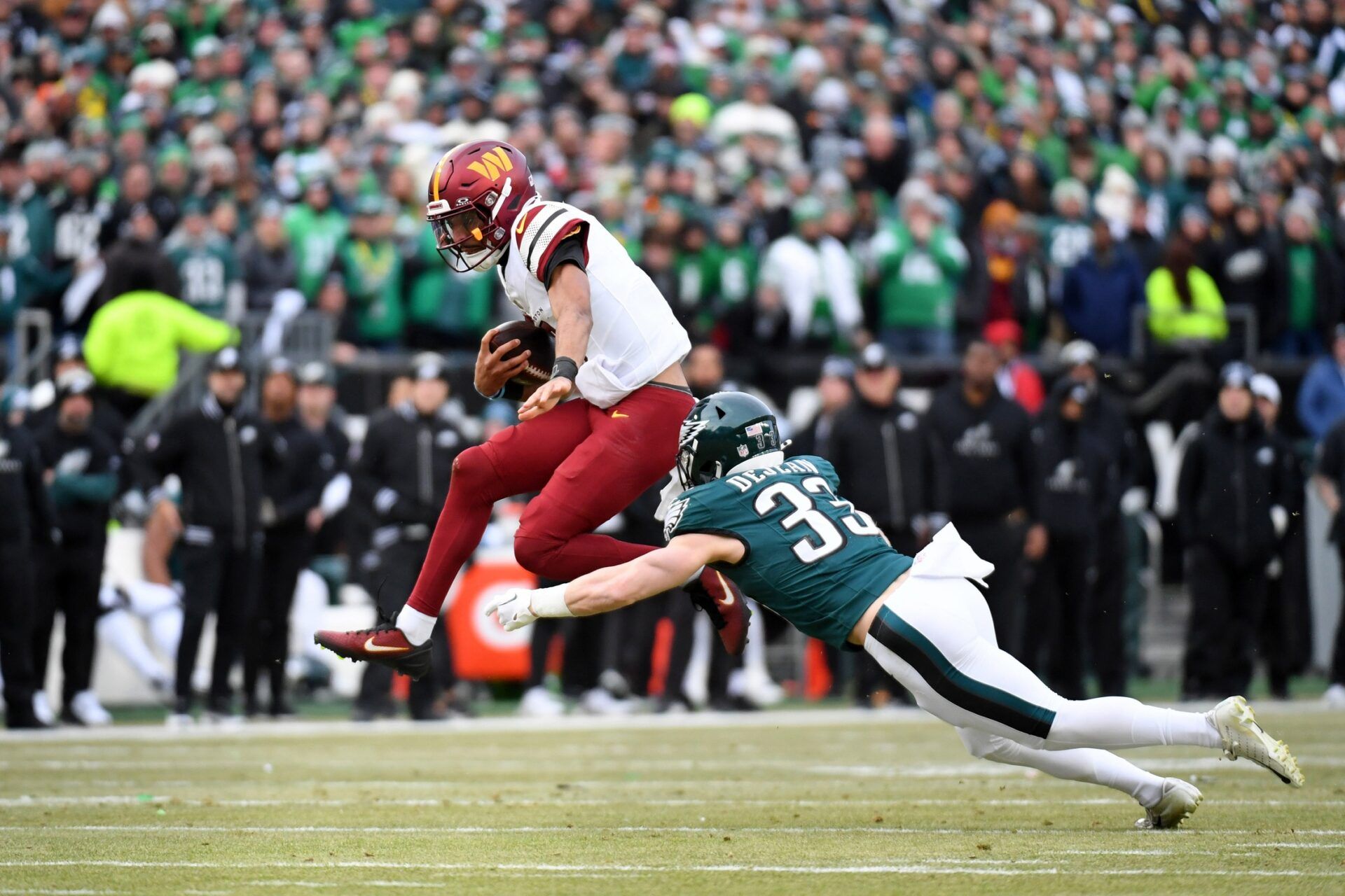 Washington Commanders quarterback Jayden Daniels (5) leaps to avoid Philadelphia Eagles cornerback Cooper DeJean (33) during the first half in the NFC Championship game at Lincoln Financial Field.