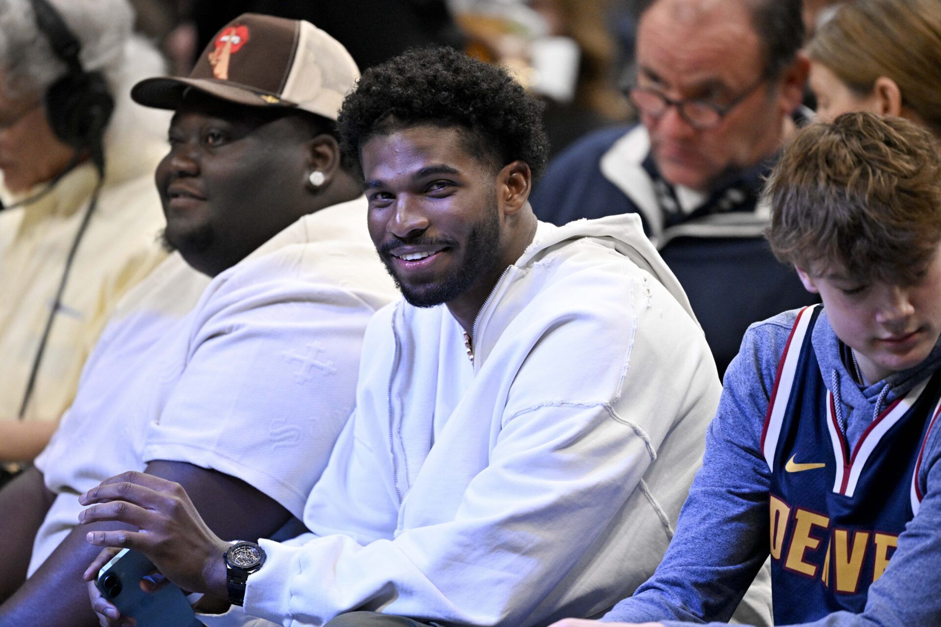 Colorado Buffaloes quarterback Shedeur Sanders smiles as he watches the game between the Dallas Mavericks and the Denver Nuggets during the second quarter at the American Airlines Center.