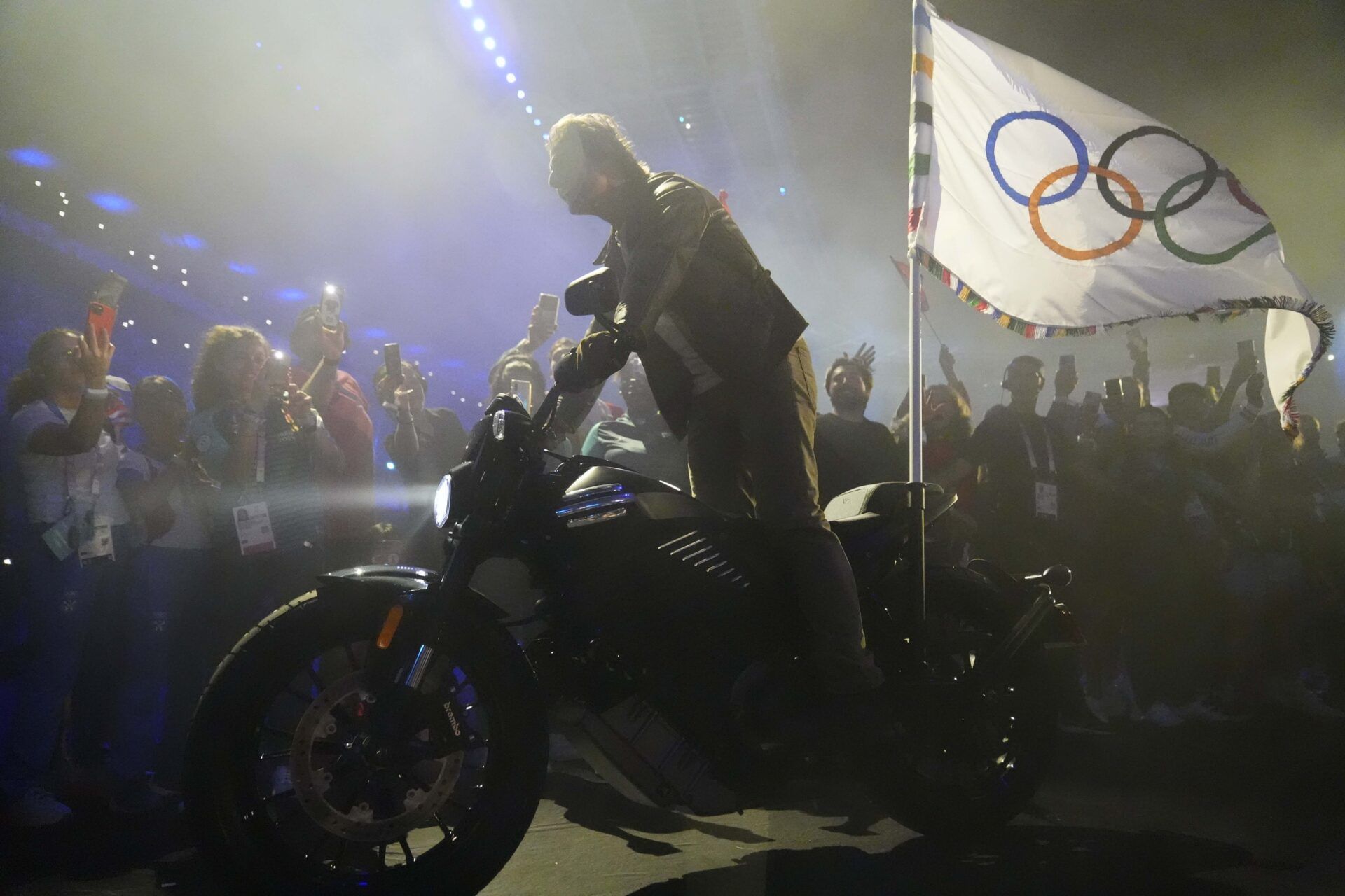 Movie actor Tom Cruise rides a motorcycle out of the stadium with the Olympic flag during the closing ceremony for the Paris 2024 Olympic Summer Games at Stade de France.