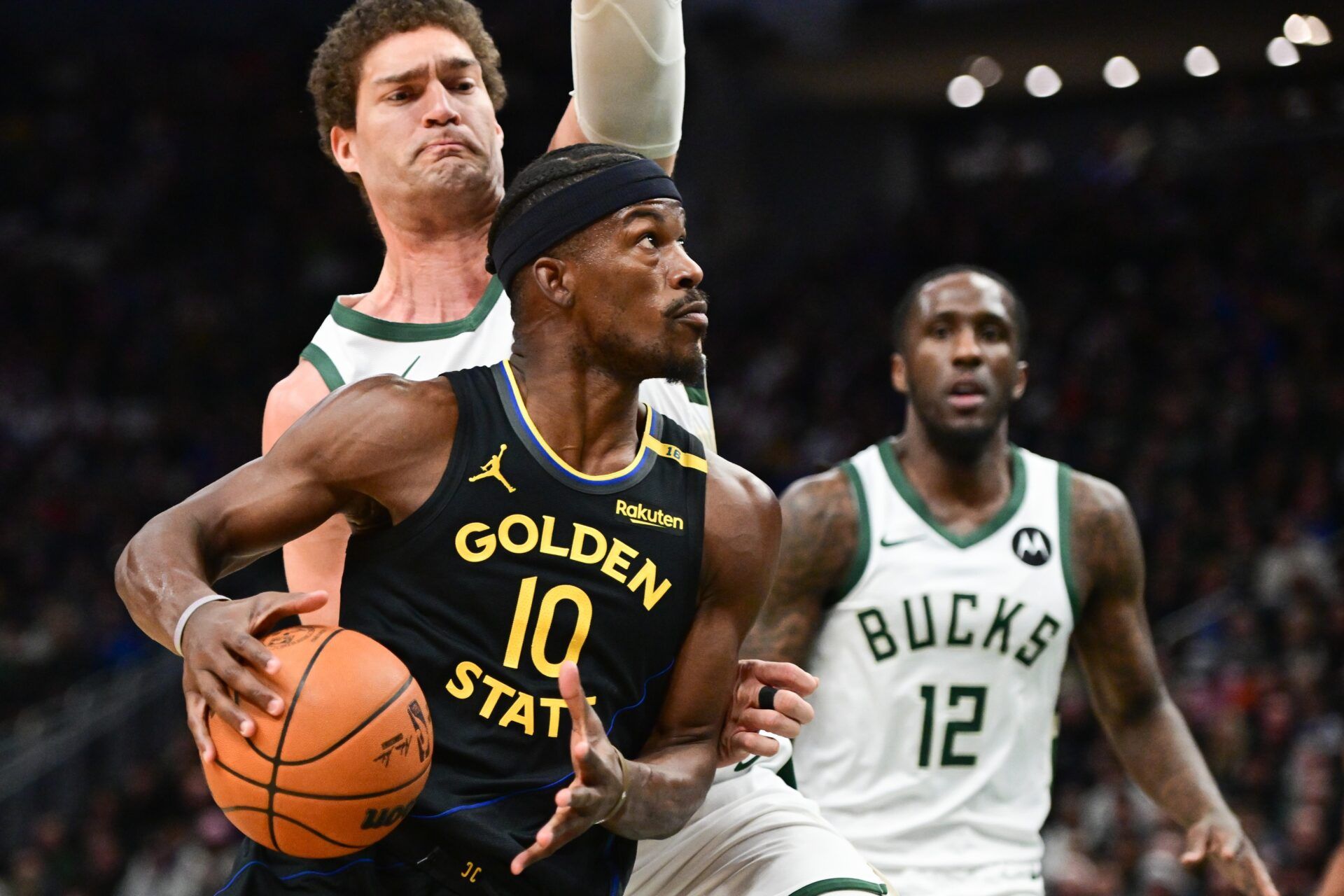 Golden State Warriors forward Jimmy Butler (10) drives for the basket against Milwaukee Bucks guard Taurean Prince (12) and center Brook Lopez (11) in the first quarter at Fiserv Forum.