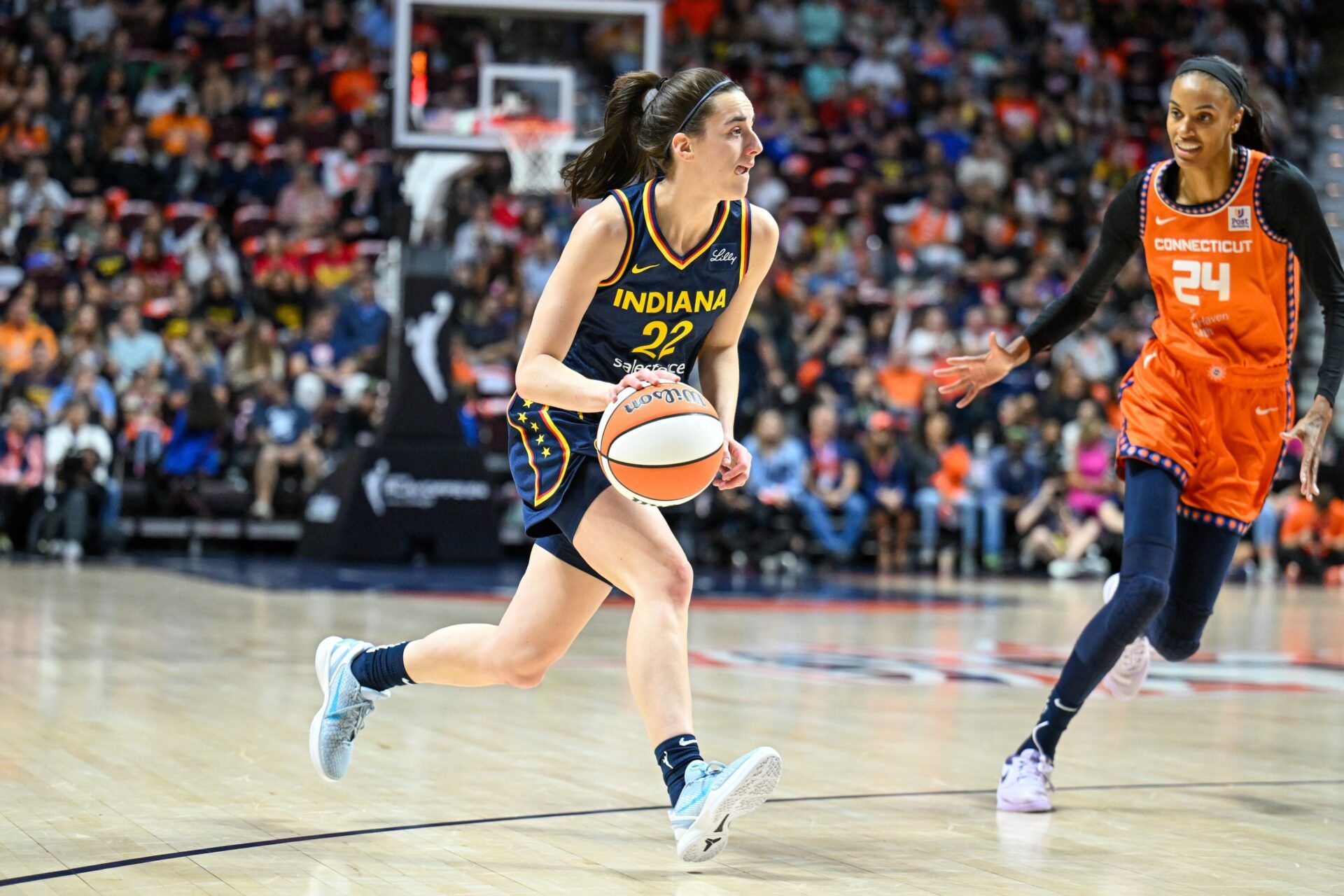 Indiana Fever guard Caitlin Clark (22) dribbles the ball chased by Connecticut Sun forward DeWanna Bonner (24) in the first quarterduring game one of the first round of the 2024 WNBA Playoffs at Mohegan Sun Arena.