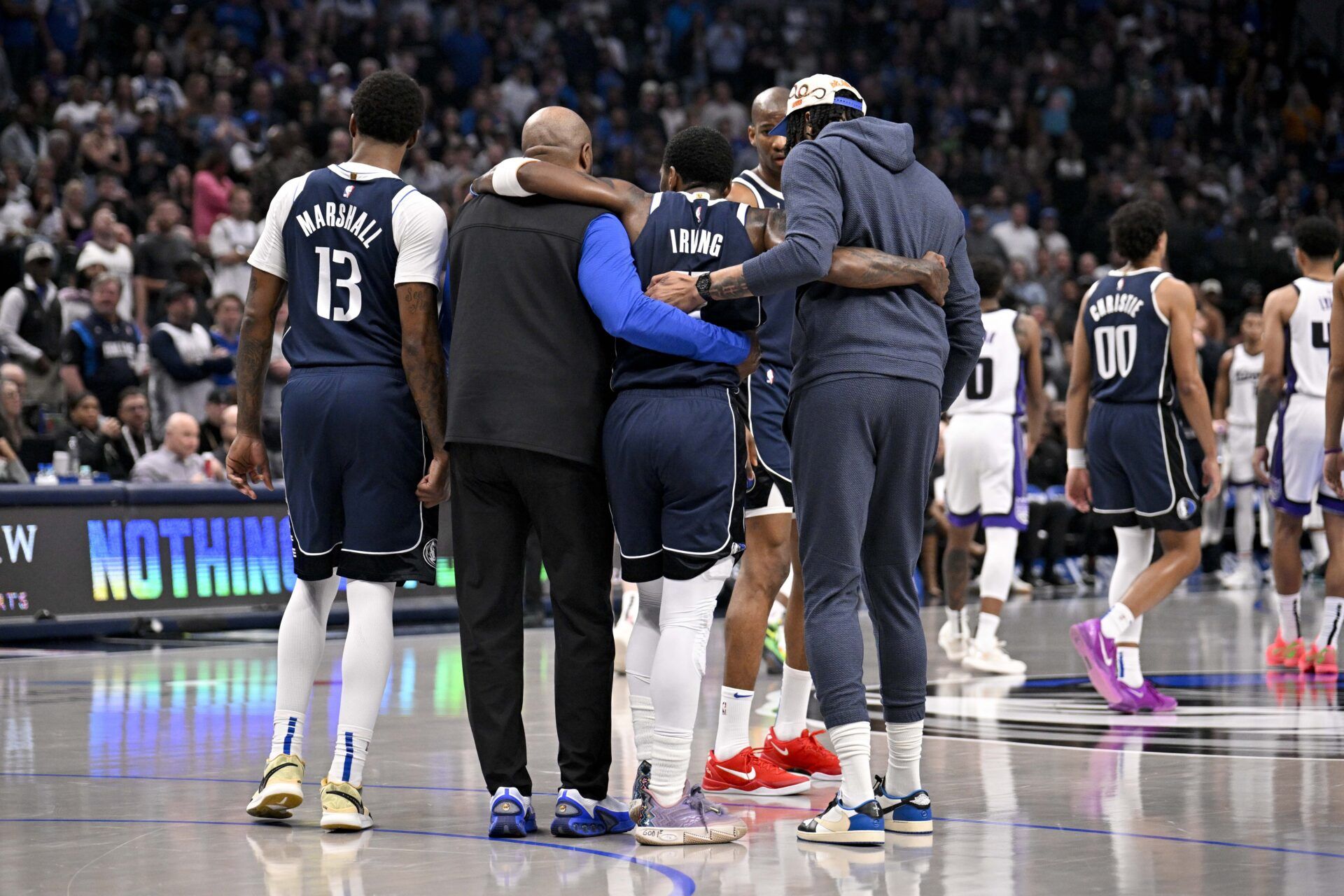 Dallas Mavericks guard Kyrie Irving (11) is helped off the court by forward Naji Marshall (13) and forward Anthony Davis (3) during the second quarter against the Sacramento Kings at the American Airlines Center.