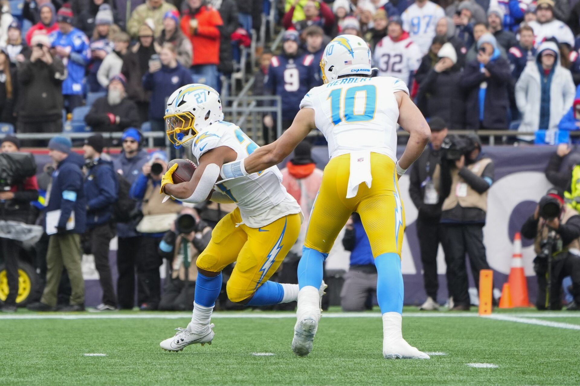 Los Angeles Chargers quarterback Justin Herbert (10) hands the ball off to running back J.K. Dobbins (27) against the New England Patriots during the first half at Gillette Stadium.