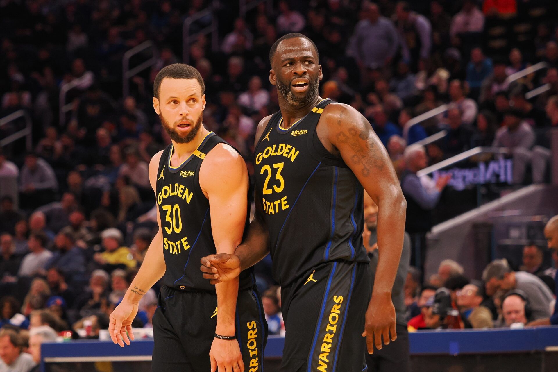 San Francisco, California, USA; Golden State Warriors guard Stephen Curry (30) and forward Draymond Green (23) look towards an Orlando Magic player at half time at Chase Center.