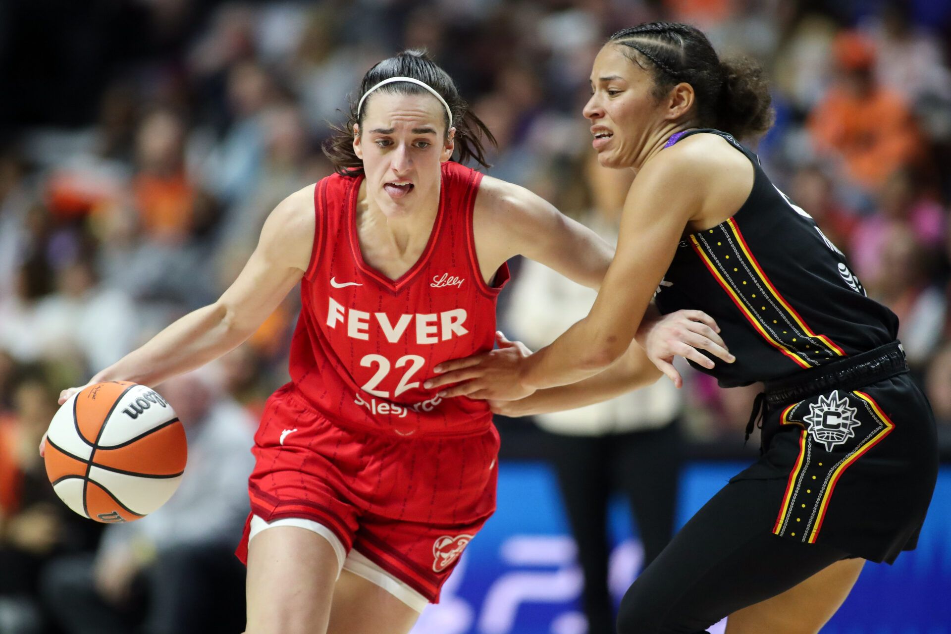 Caitlin Clark dribbles the basketball against a defender.