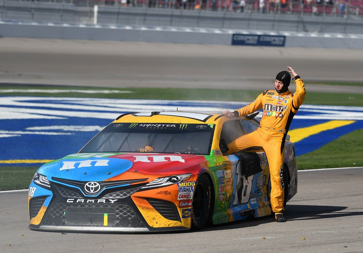 Kyle Busch (18) climbs out of the smoking cab of his car at the conclusion of the Kobalt 400 at Las Vegas Motor Speedway. Martin Truex Jr. won the race.