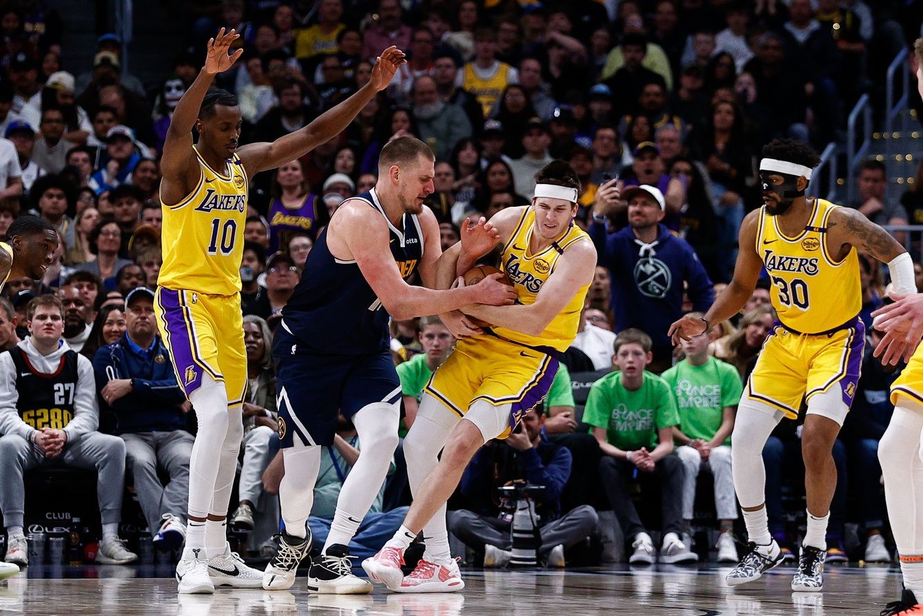 Los Angeles Lakers guard Austin Reaves (15) steals the ball away from Denver Nuggets center Nikola Jokic (15) as center Christian Koloko (10) and guard Jordan Goodwin (30) defend in the fourth quarter at Ball Arena.