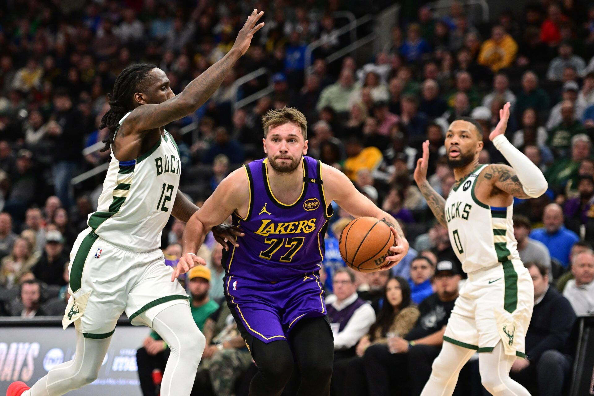 Los Angeles Lakers guard Luka Doncic (77) drives to the basket between Milwaukee Bucks guard Taurean Prince (12) and guard Damian Lillard (0) in the third quarter at Fiserv Forum.