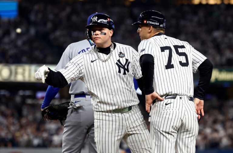 New York Yankees outfielder Alex Verdugo (24) celebrates with first base coach Travis Chapman (75) after hitting a RBI single during the second inning against the Los Angeles Dodgers in game five of the 2024 MLB World Series at Yankee Stadium.