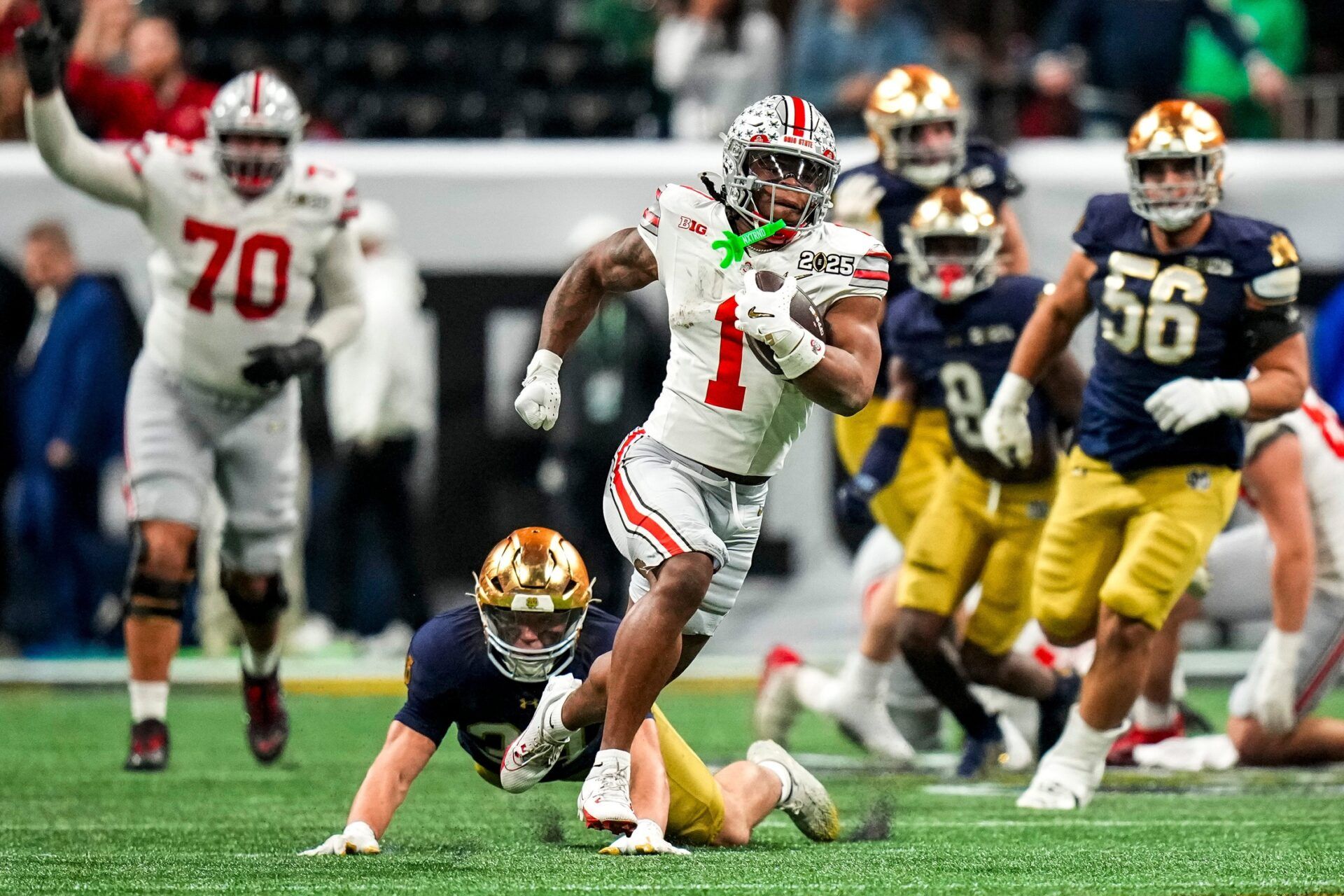 Ohio State Buckeyes running back Quinshon Judkins (1) runs the ball against the Notre Dame Fighting Irish during the College Football Playoff championship at Mercedes-Benz Stadium in Atlanta on Jan. 20, 2025. Ohio State Buckeyes tight end Gee Scott Jr. (88)