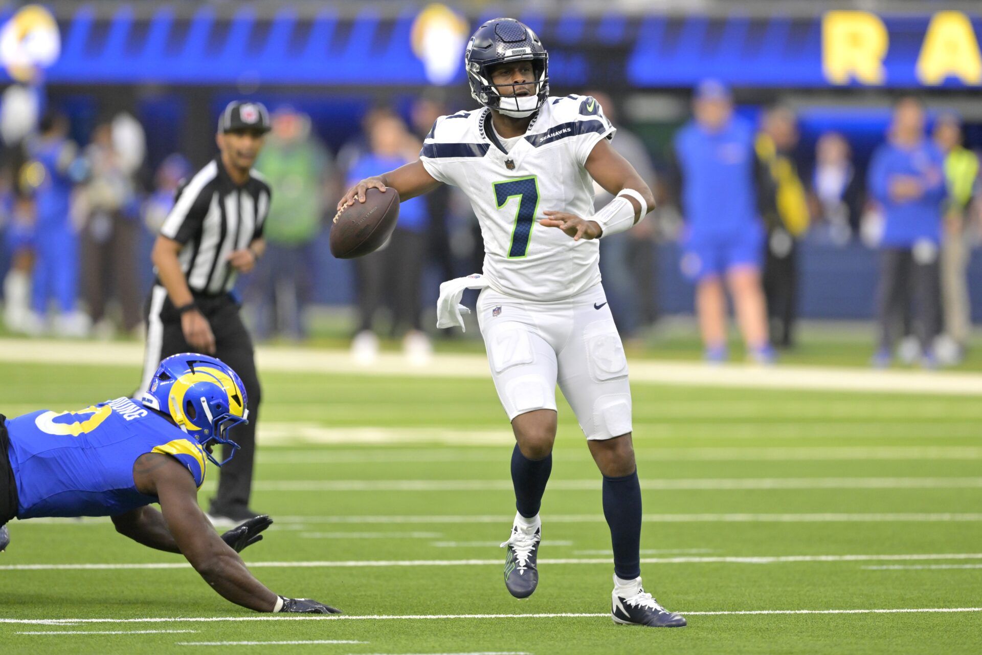 Seattle Seahawks quarterback Geno Smith (7) scrambles away from Los Angeles Rams linebacker Byron Young (0) and throws for a touchdown in the first half at SoFi Stadium.