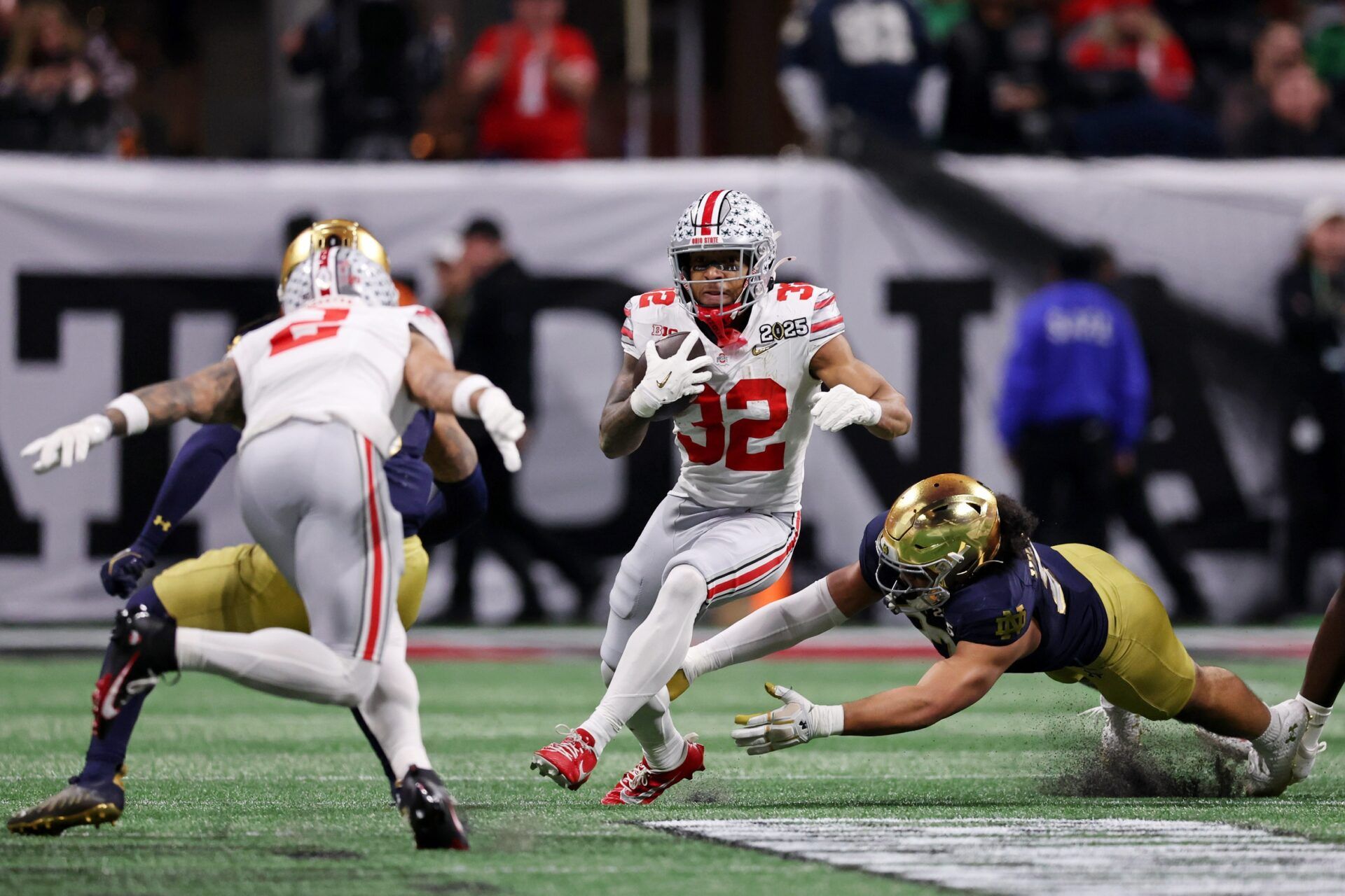 Ohio State Buckeyes running back TreVeyon Henderson (32) runs with the ball against the Notre Dame Fighting Irish during the first half the CFP National Championship college football game at Mercedes-Benz Stadium.