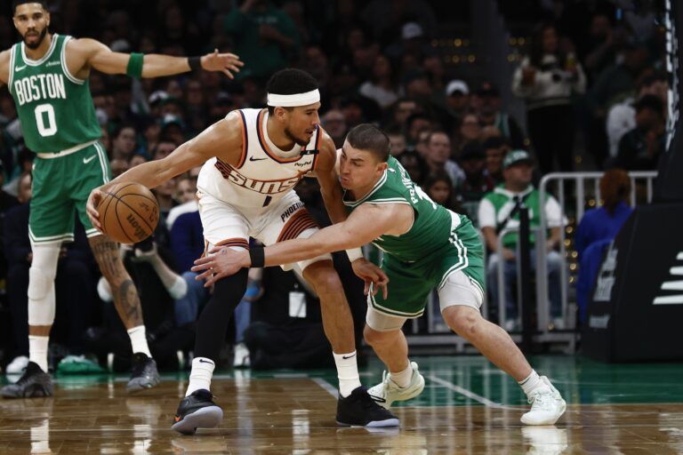 Boston Celtics guard Payton Pritchard (11) tries to knock the ball away from Phoenix Suns guard Devin Booker (1) during the first quarter at TD Garden.