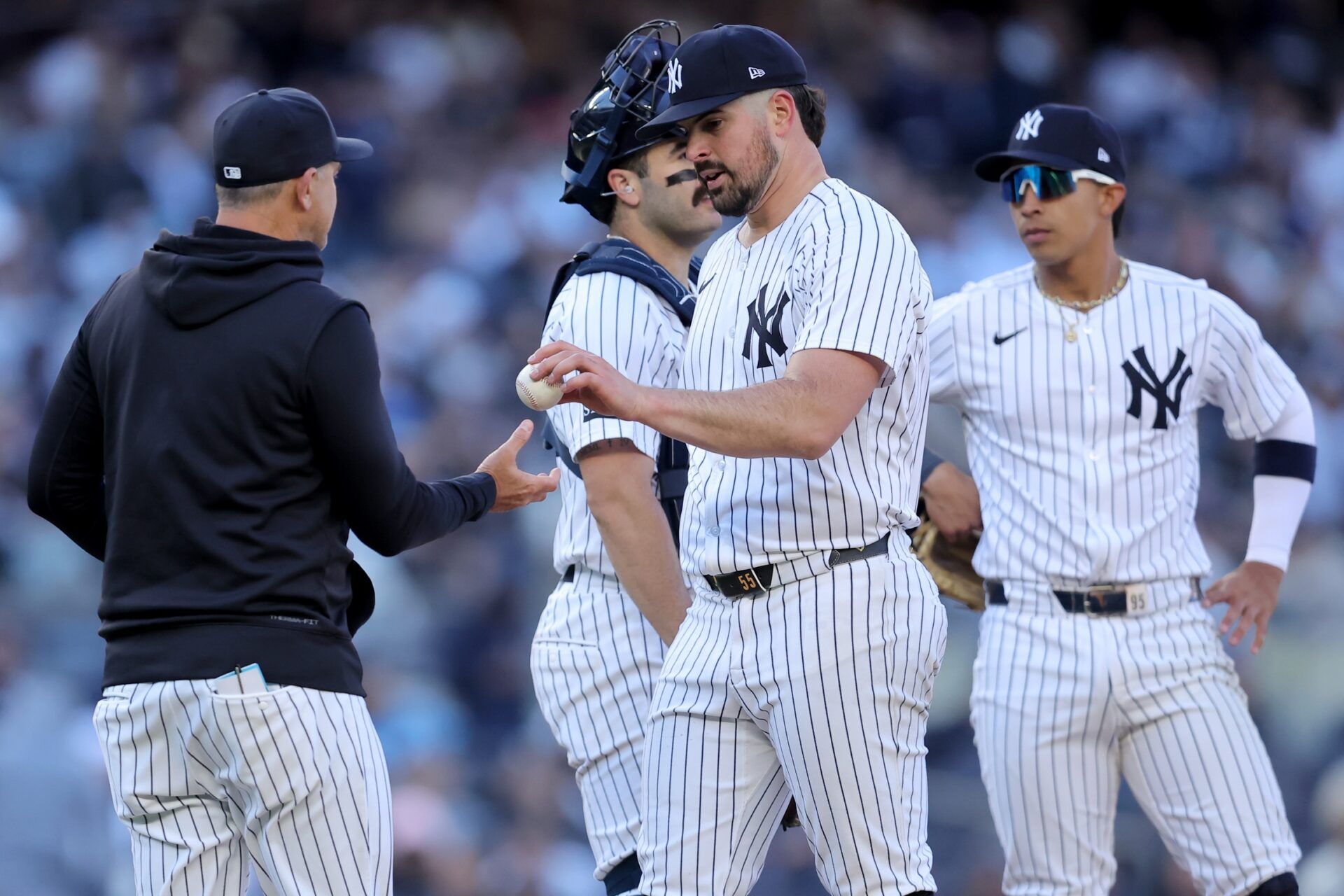 New York Yankees starting pitcher Carlos Rodon (55) hands the ball to manager Aaron Boone (17) after being relieved during the sixth inning against the Milwaukee Brewers at Yankee Stadium.