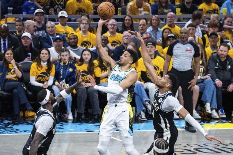 Indiana Pacers guard Tyrese Haliburton (0) shoots the ball while Milwaukee Bucks forward Bobby Portis (9) and forward Giannis Antetokounmpo (34) defend in the second half at Gainbridge Fieldhouse.