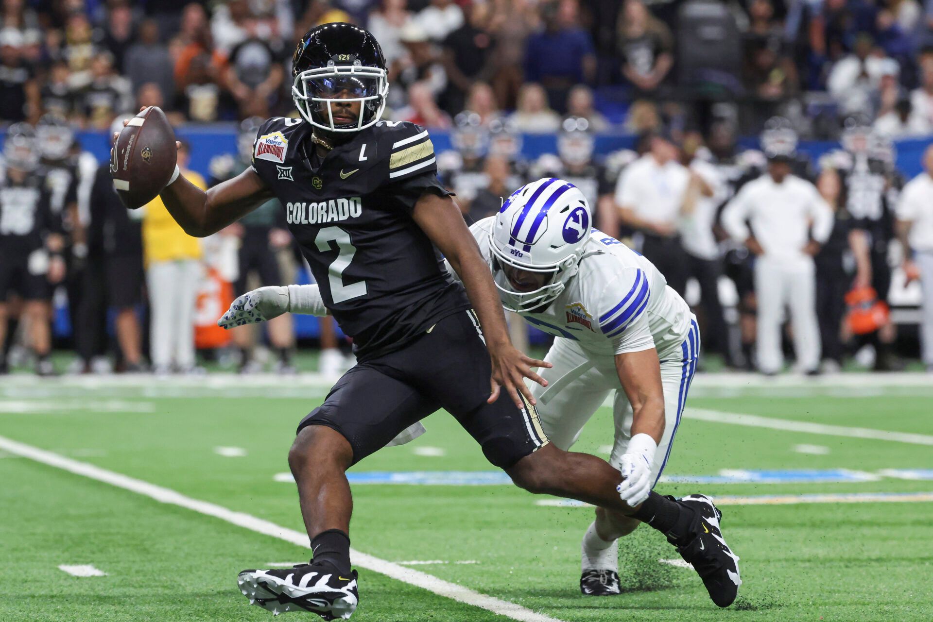 Dec 28, 2024; San Antonio, TX, USA; Colorado Buffaloes quarterback Shedeur Sanders (2) attempts to avoid a tackle by Brigham Young Cougars safety Raider Damuni (3) during the second quarter at Alamodome. Mandatory Credit: Troy Taormina-Imagn Images