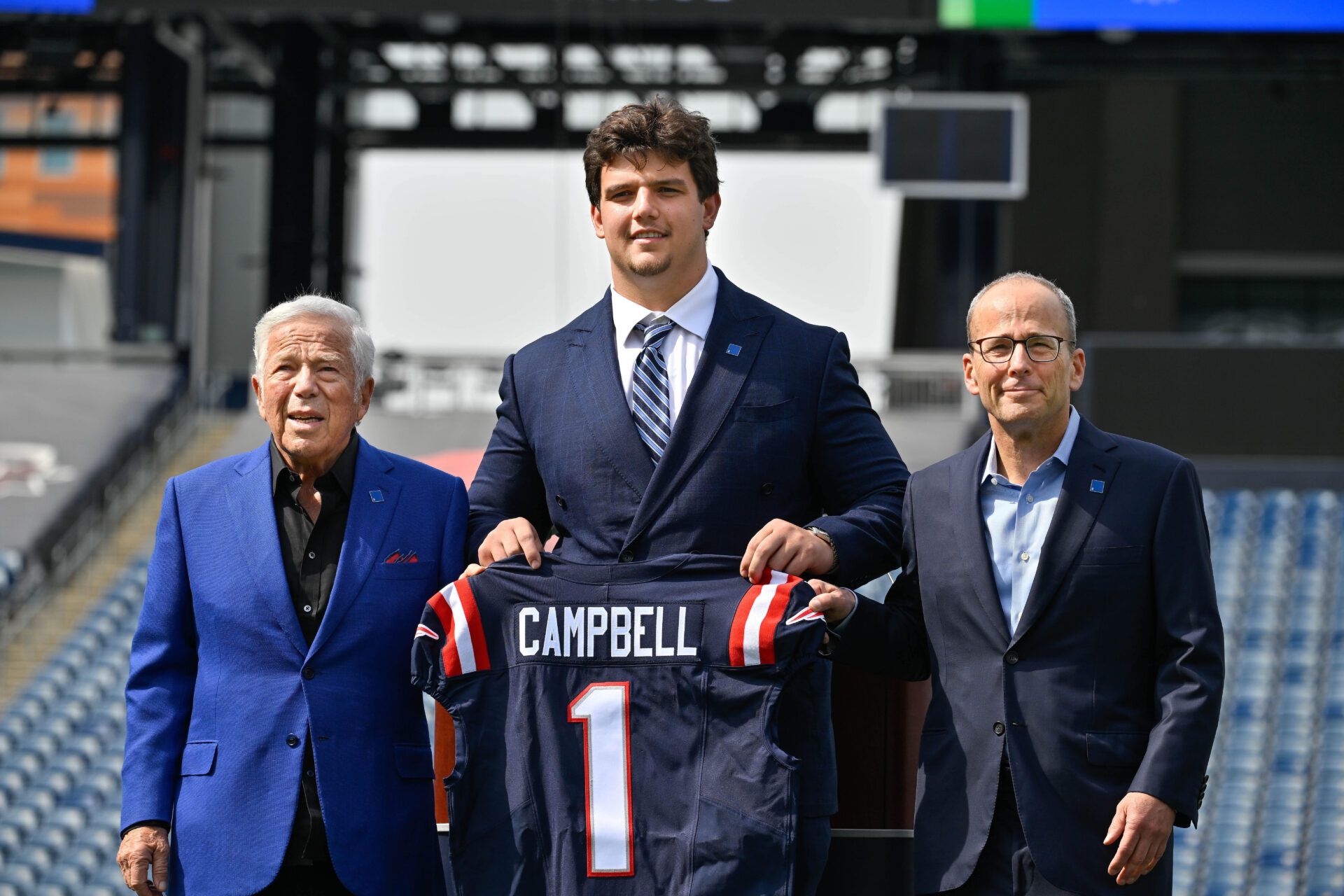 Apr 25, 2025; Foxborough, MA, USA; New England Patriots first round draft pick Will Campbell is presented with a ceremonial first round jersey by team owner Robert Kraft (l) and team president Jonathan Kraft (r) at a press conference on the game field at Gillette Stadium. Mandatory Credit: Eric Canha-Imagn Images