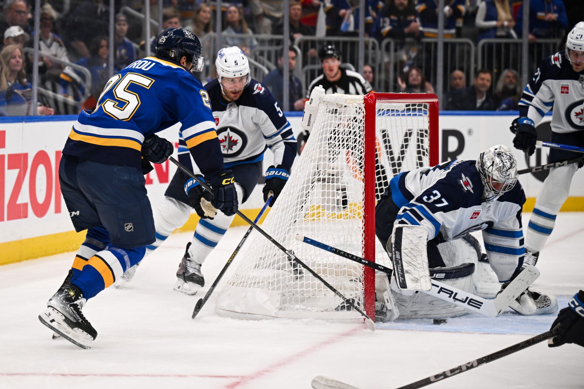 May 2, 2025; St. Louis, Missouri, USA; Winnipeg Jets defenseman Luke Schenn (5) and goaltender Connor Hellebuyck (37) defend the net against St. Louis Blues right wing Jordan Kyrou (25) in game six of the first round of the 2025 Stanley Cup Playoffs at Enterprise Center. Mandatory Credit: Connor Hamilton-Imagn Images