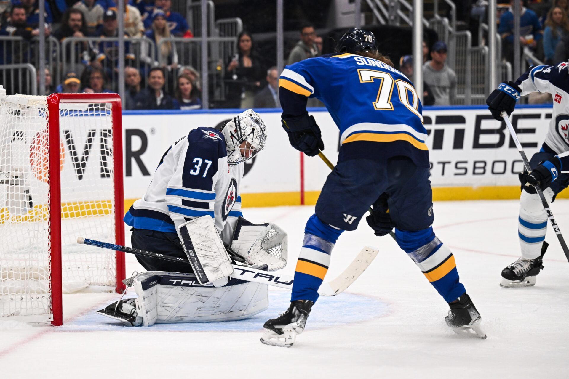 May 2, 2025; St. Louis, Missouri, USA; Winnipeg Jets goaltender Connor Hellebuyck (37) defends the net against St. Louis Blues center Oskar Sundqvist (70) during the second period in game six of the first round of the 2025 Stanley Cup Playoffs at Enterprise Center. Mandatory Credit: Connor Hamilton-Imagn Images