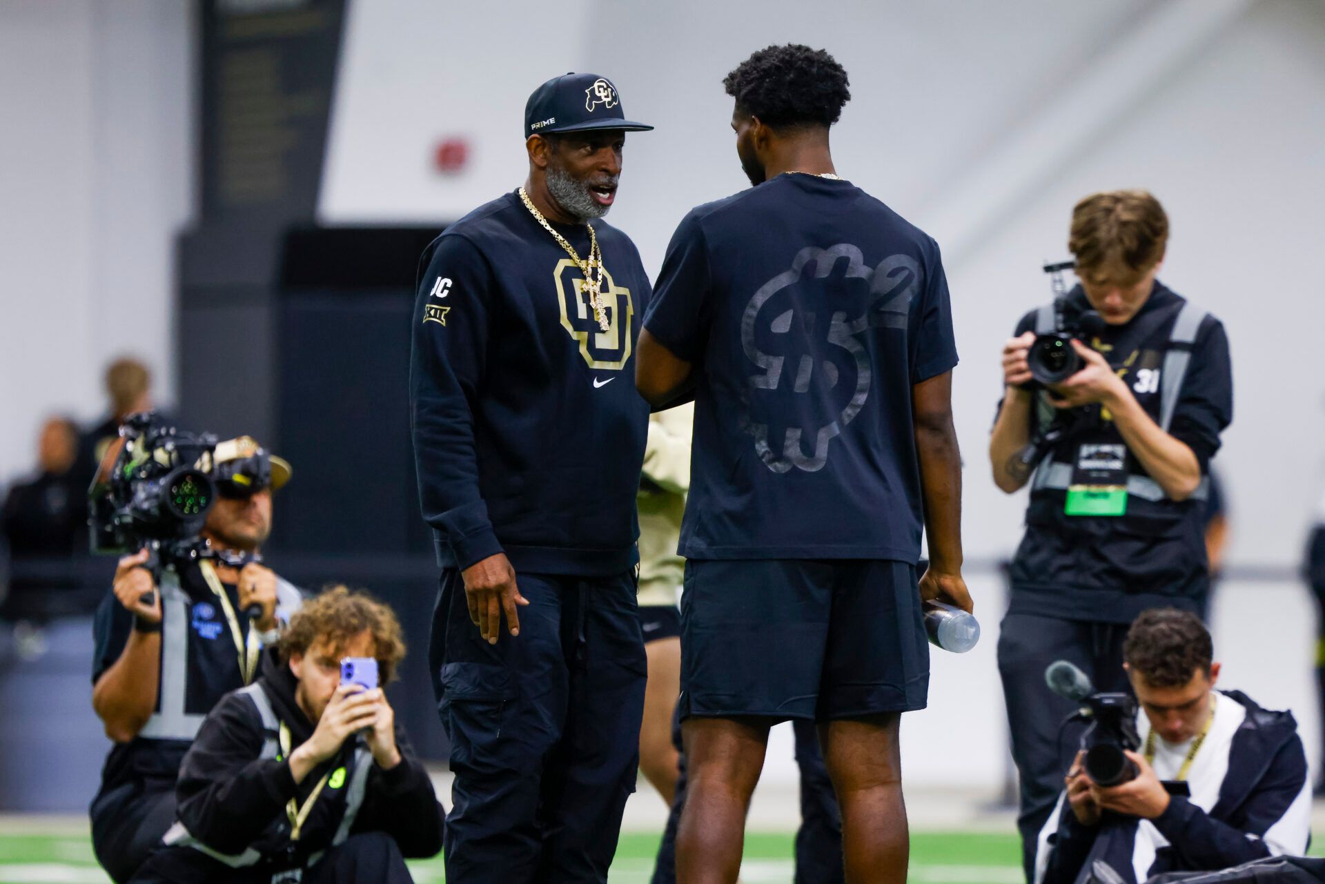 Apr 4, 2025; Boulder, CO, USA; Colorado Buffaloes head coach Deion Sanders talks to his son, Colorado Buffaloes quarterback Shedeur Sanders (2), at the University of Colorado NFL Showcase at the CU Indoor Practice Facility. Mandatory Credit: Michael Ciaglo-Imagn Images