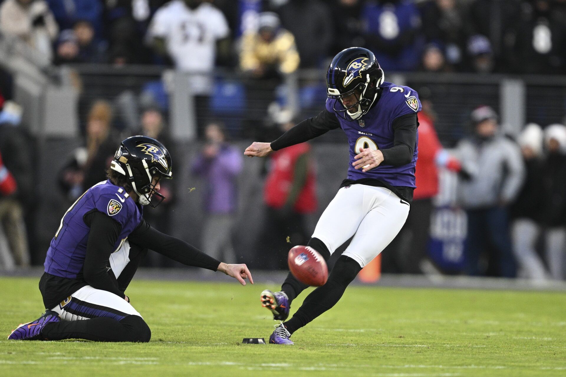 Jan 4, 2025; Baltimore, Maryland, USA; Baltimore Ravens place kicker Justin Tucker (9) kicks off as punter Jordan Stout (11) holds during the first quarter against the Cleveland Browns at M&T Bank Stadium. Mandatory Credit: Tommy Gilligan-Imagn Images