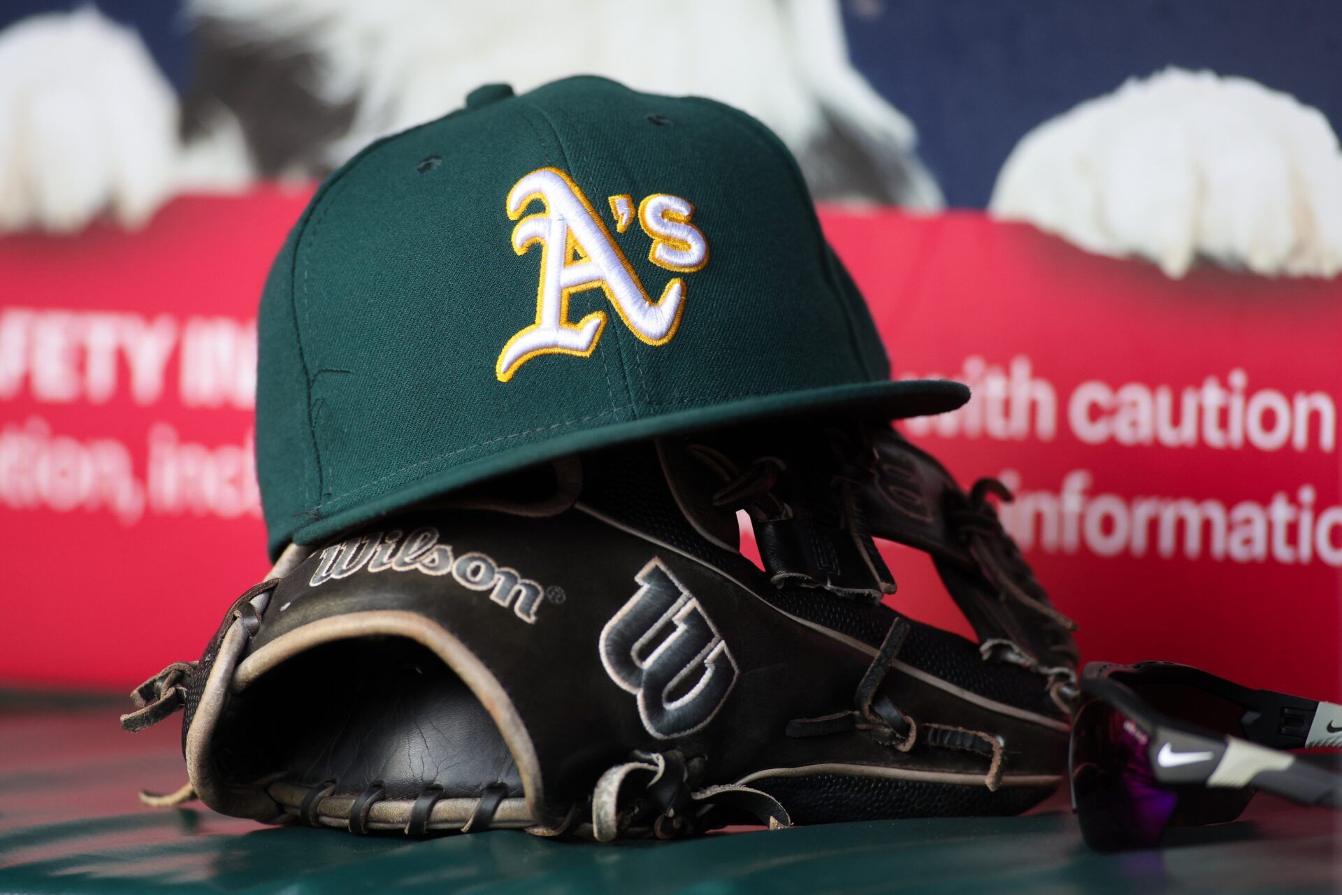 A detailed view of an Oakland Athletics hat and glove on the field against the Atlanta Braves in the sixth inning at Truist Park.