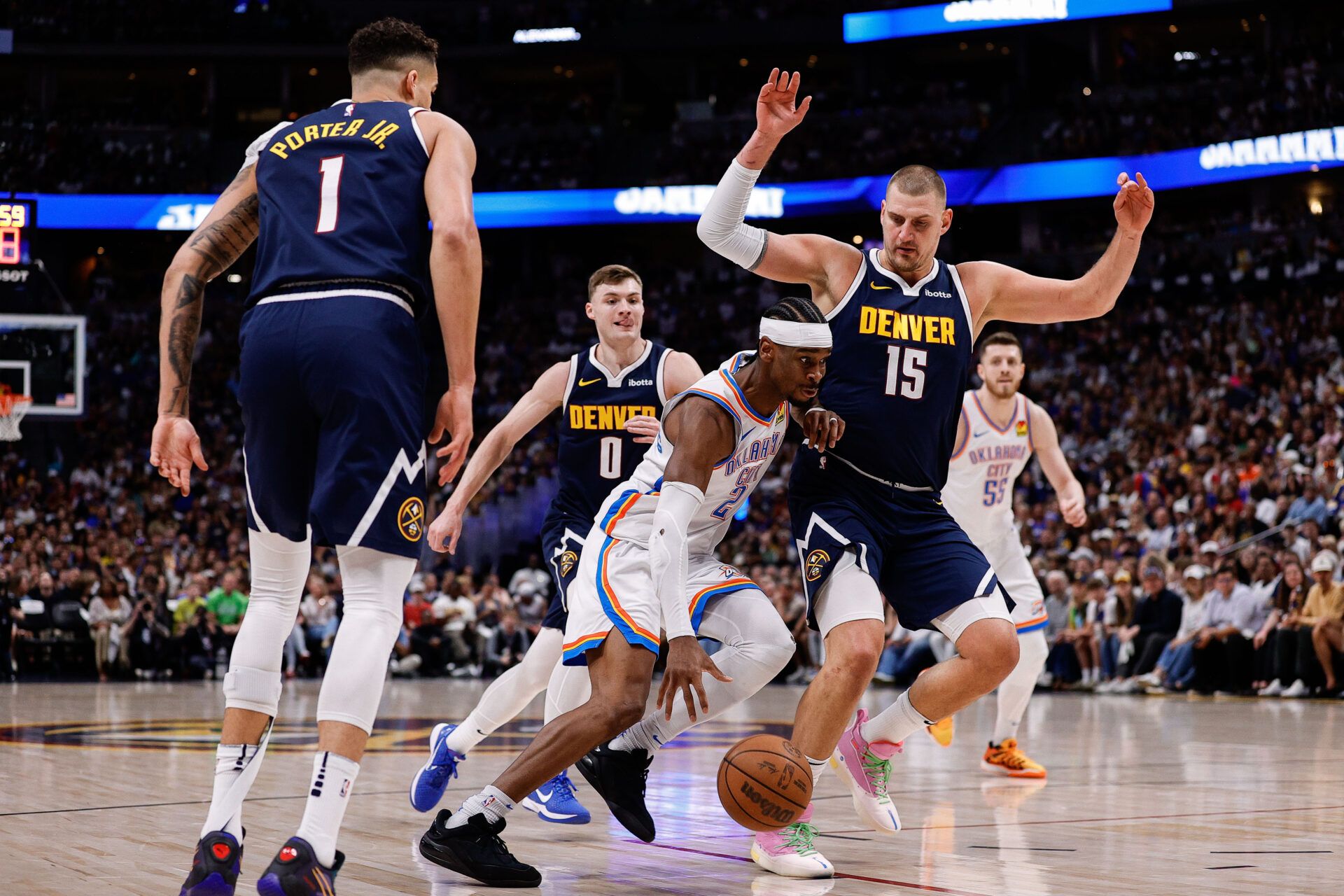 Oklahoma City Thunder guard Shai Gilgeous-Alexander (2) controls the ball against Denver Nuggets center Nikola Jokic (15) and guard Christian Braun (0) and forward Michael Porter Jr. (1) in the first quarter during game four of the second round of the 2025 NBA Playoffs at Ball Arena.