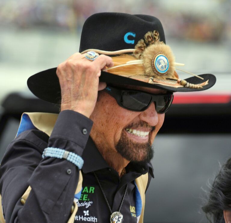 Richard Petty holds onto his cowboy hat as strong gust of wind and a rain storm approaches, Sunday February 16, 2025 during the Daytona 500 at Daytona International Speedway.