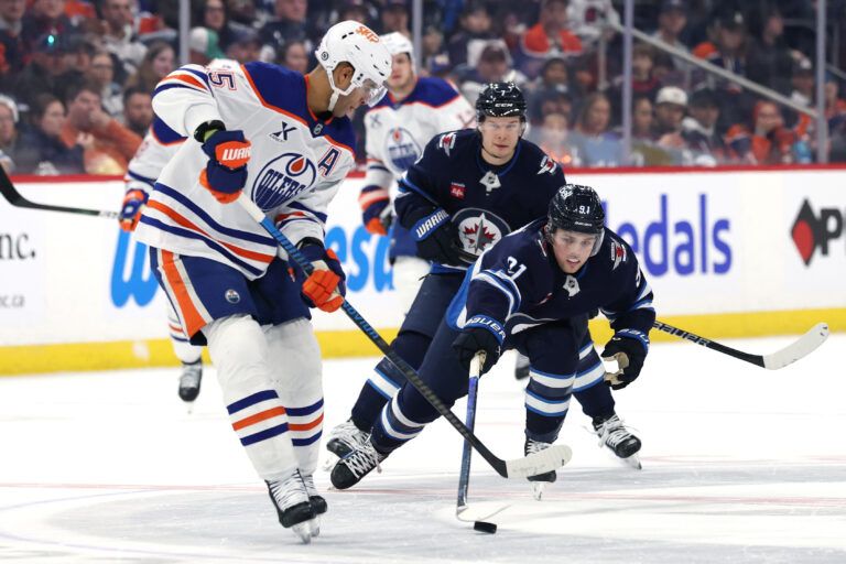 Winnipeg Jets center Cole Perfetti (91) poke checks Edmonton Oilers defenseman Darnell Nurse (25) in the second period at Canada Life Centre.
