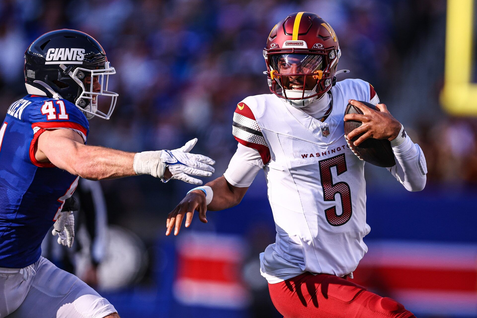 Washington Commanders quarterback Jayden Daniels (5) scrambles away from New York Giants linebacker Micah McFadden (41) during the first half at MetLife Stadium.