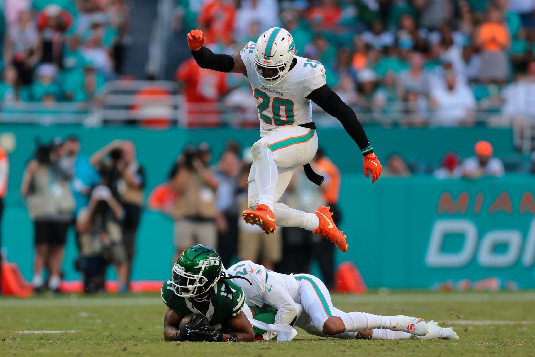 Miami Dolphins linebacker Jordyn Brooks (20) jumps over safety Jordan Poyer (21) and New York Jets wide receiver Davante Adams (17) during the fourth quarter at Hard Rock Stadium.