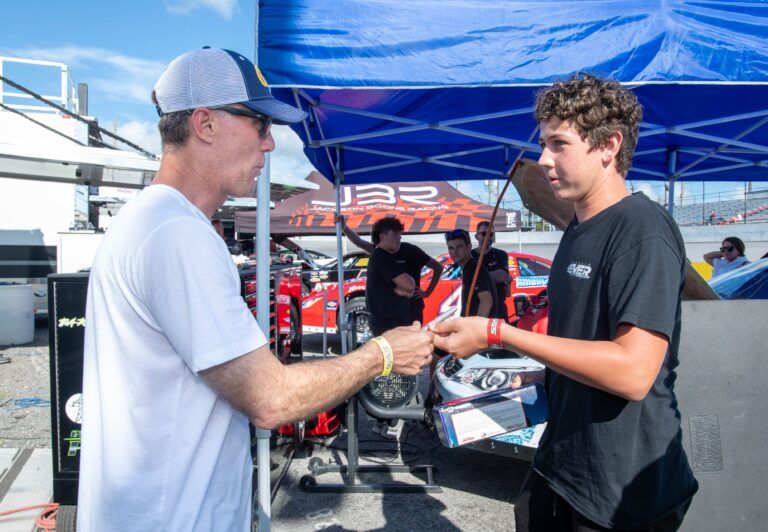 2014 NASCAR Cup Series champion Kevin Harvick, left, hands Dean O'Neill, 14, of Navarre, his pen after giving him an autograph prior to the races at the Five Flags Speedway in Pensacola on Friday, June 28, 2024.