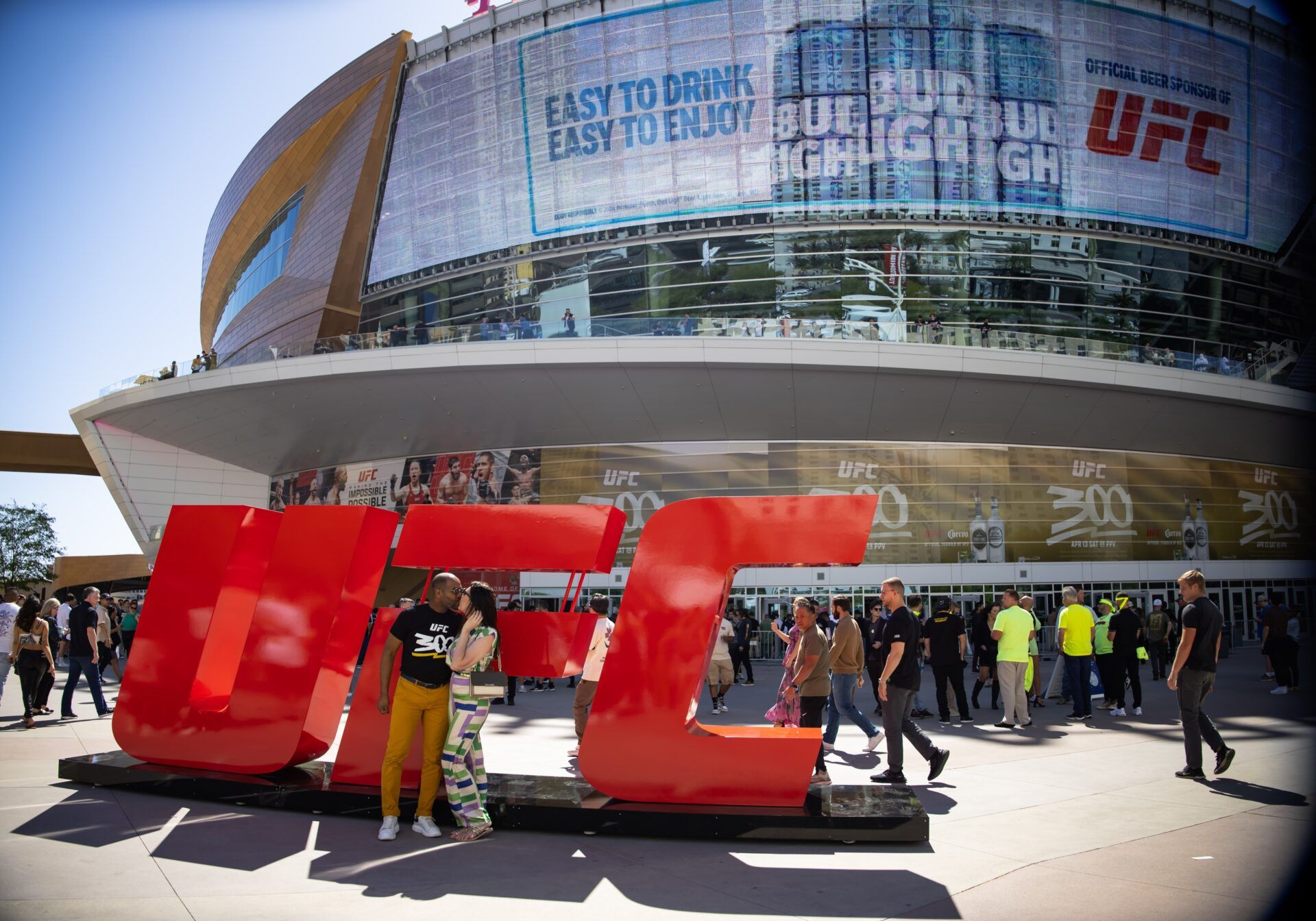 A couple kisses in front of a UFC logo prior to UFC 300 at T-Mobile Arena.