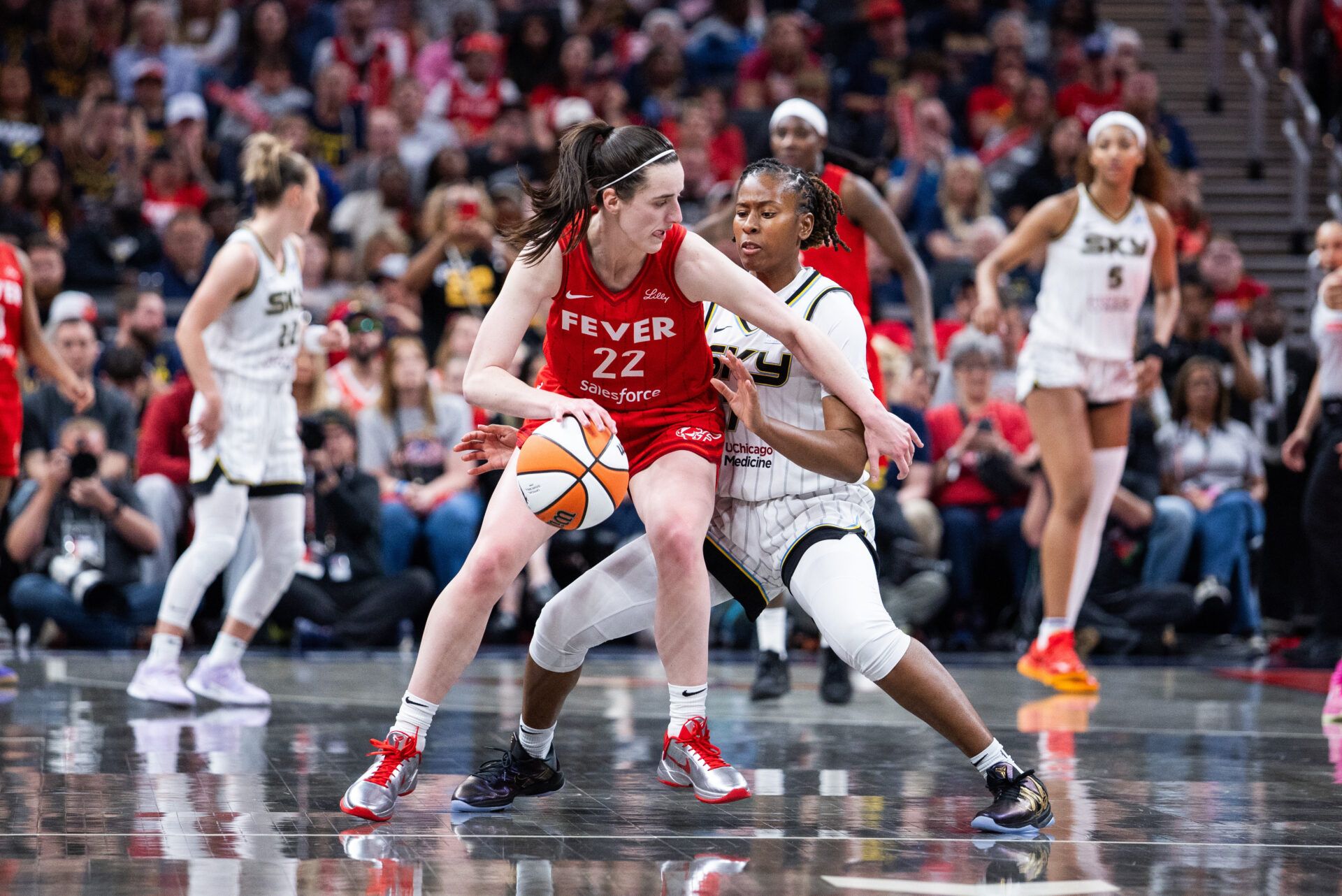Indiana Fever guard Caitlin Clark (22) dribbles  the ball while Chicago Sky guard Ariel Atkins (7) defends in the second half at Gainbridge Fieldhouse.