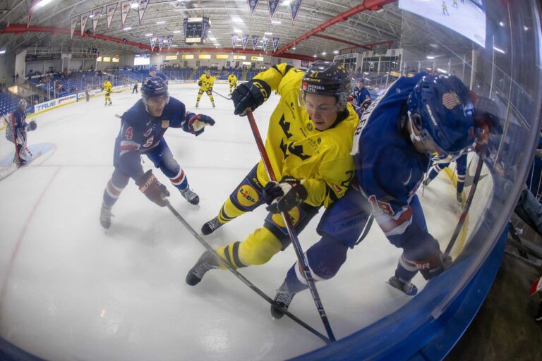 Sweden's forward David Granberg (27) battles for the puck with USA’s Logan Hensler (18) during the third period of the 2024 World Junior Summer Showcase at USA Hockey Arena.