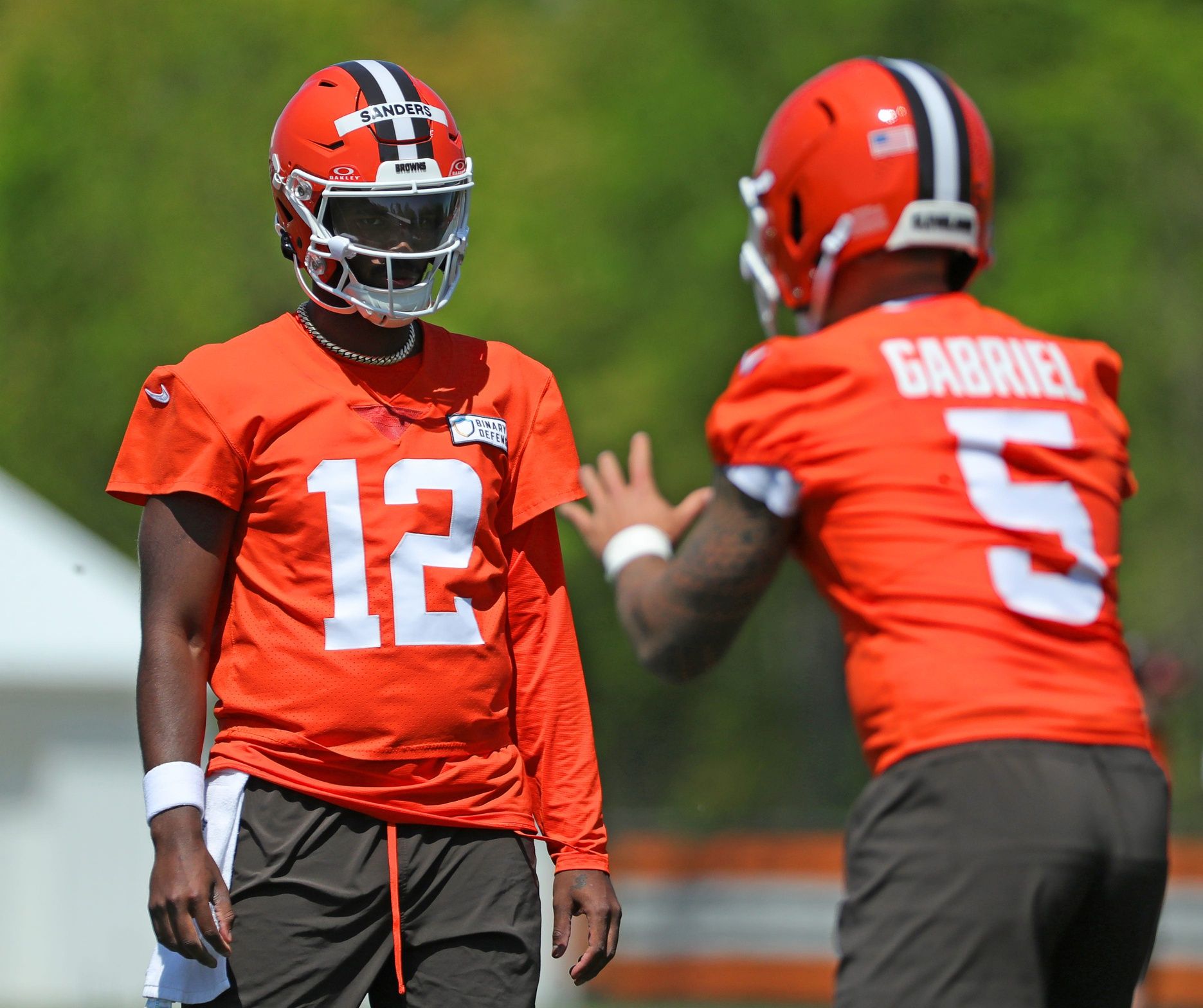 Cleveland Browns quarterback Shedeur Sanders (12) watches quarterback Dillon Gabriel (5) during day two of NFL rookie minicamp at the Cleveland Browns training facility on Saturday, May 10, 2025, in Berea, Ohio.