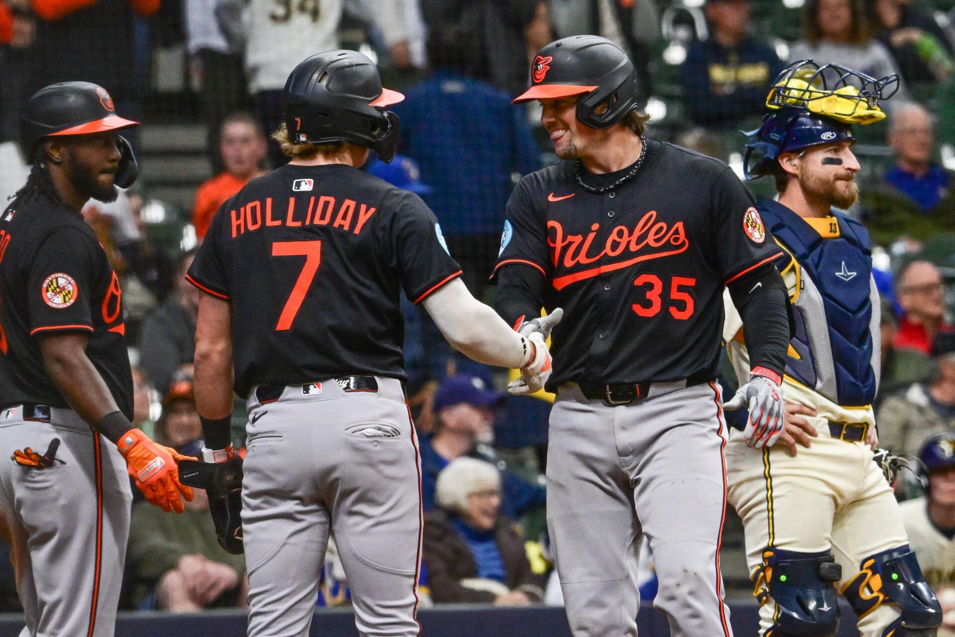 Baltimore Orioles catcher Adley Rutschman (35) is greeted by second baseman Jackson Holliday (7) after hitting a 3-run home run in the eleventh inning as Milwaukee Brewers catcher Eric Haase (13) looks on at American Family Field.