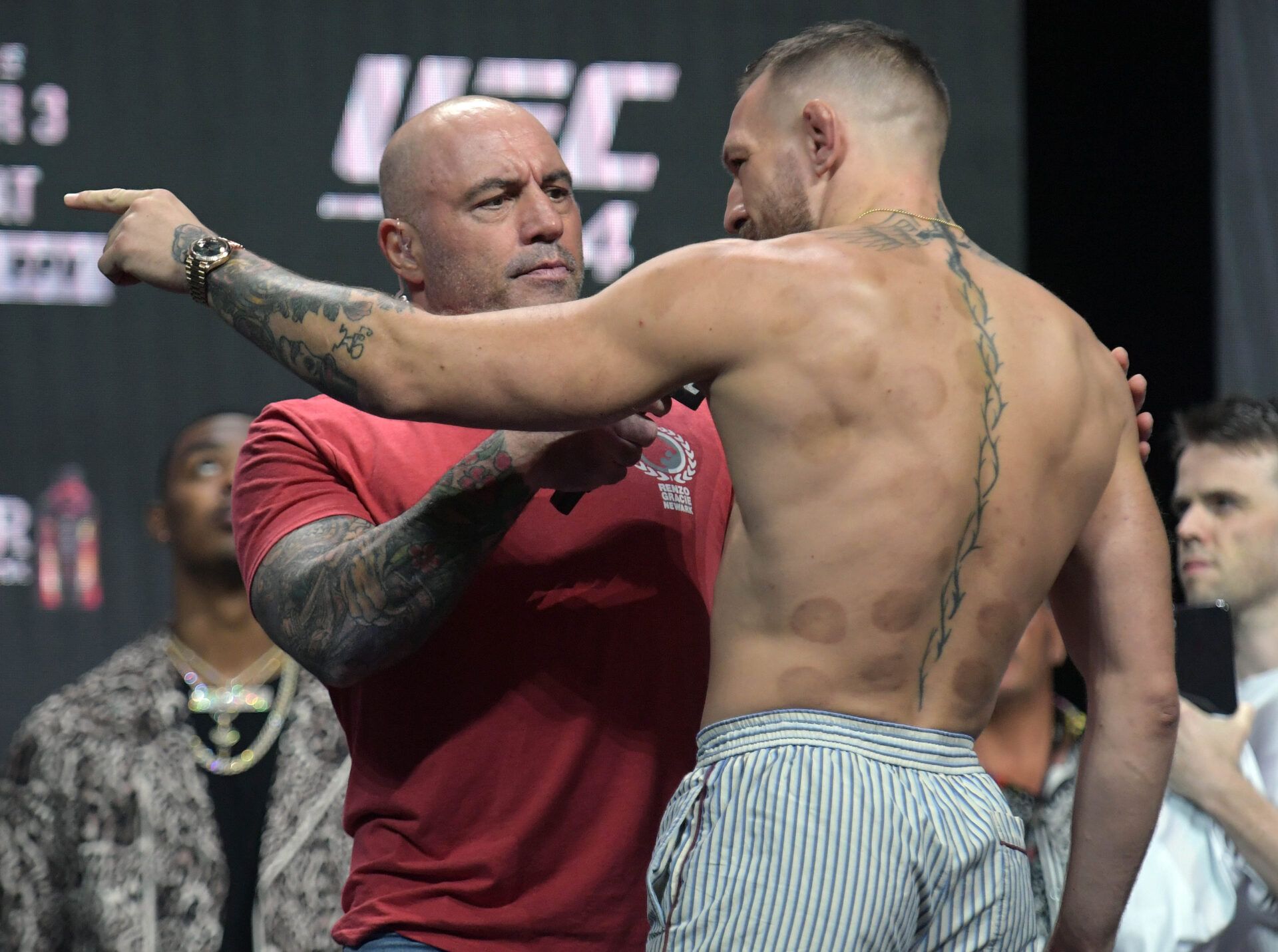 Conor McGregor motions toward Dustin Poirier while being interviewed by host Joe Rogan during weigh ins for UFC 264 at T-Mobile Arena.