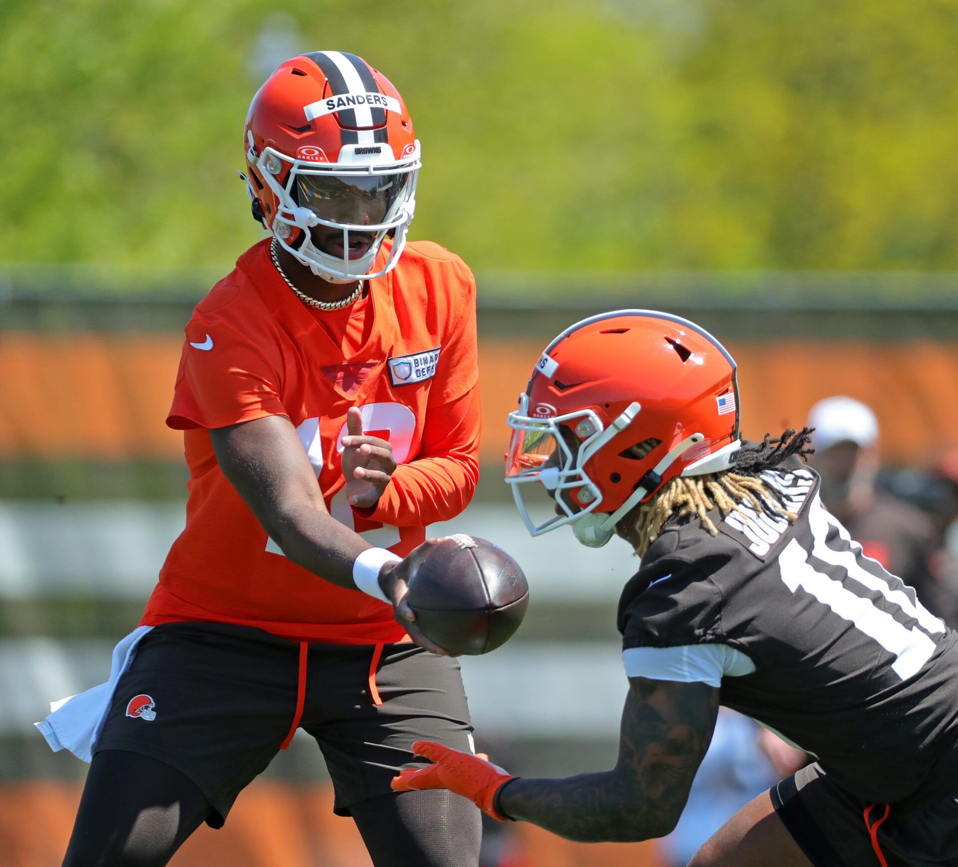 Cleveland Browns quarterback Shedeur Sanders (12) hands the ball off to Cleveland Browns running back Quinshon Judkins (10) during day two of NFL rookie minicamp at the Cleveland Browns training facility on Saturday, May 10, 2025, in Berea, Ohio.