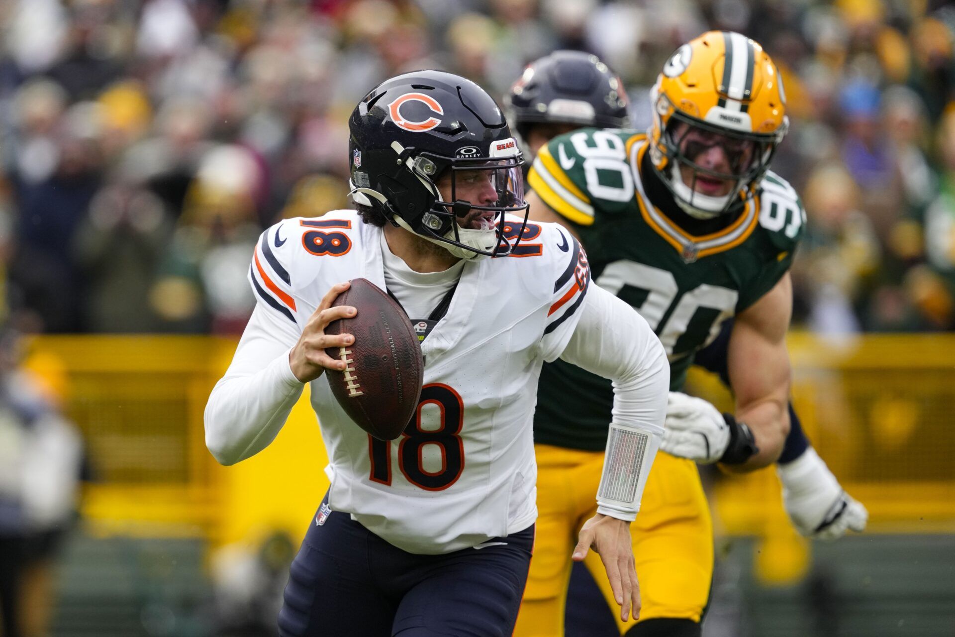 Chicago Bears quarterback Caleb Williams (18) scrambles away from pressure applied by Green Bay Packers defensive lineman Lukas Van Ness (90) during the first quarter at Lambeau Field.